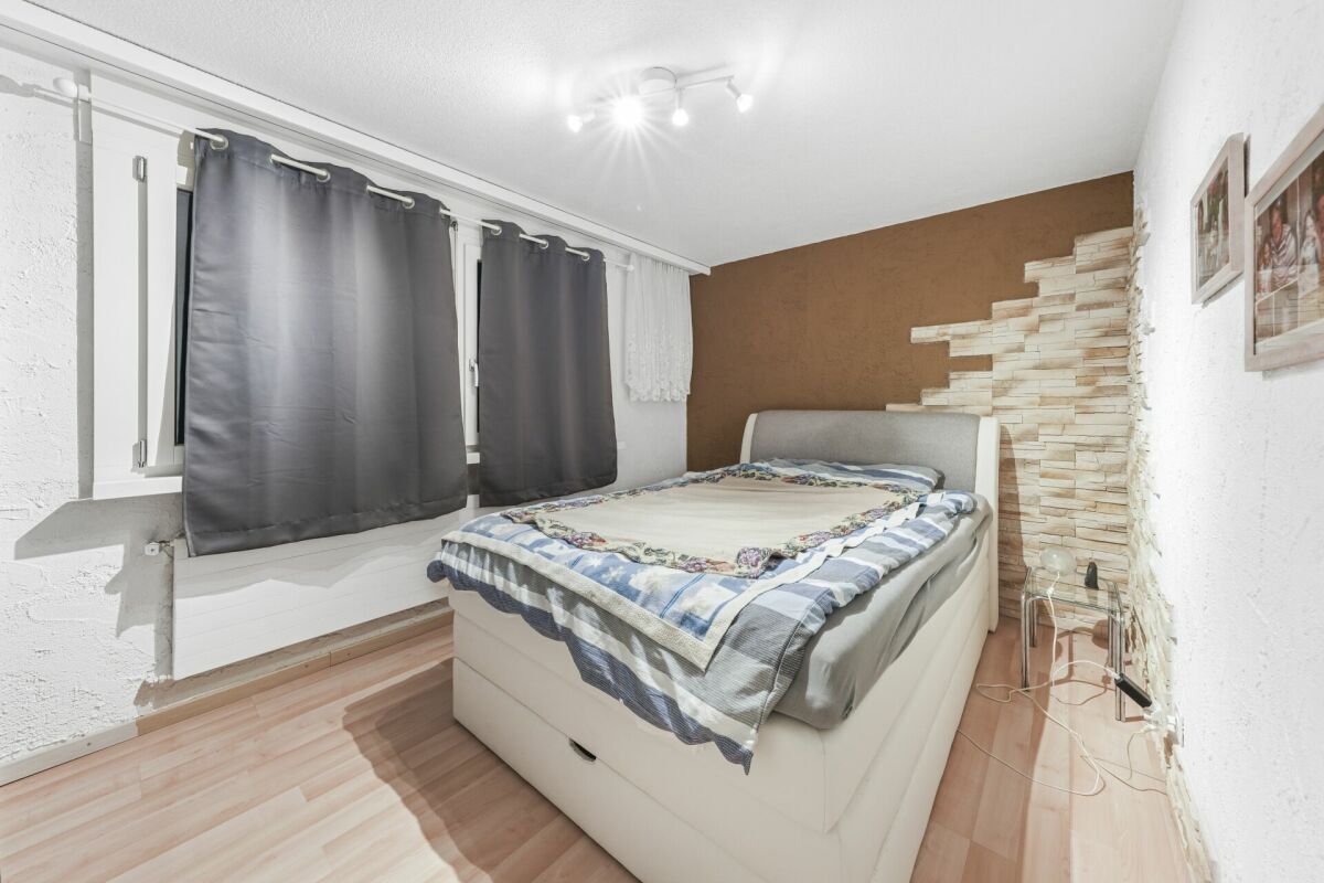 Schlafzimmer mit Einzelbett und dunklen Vorhängen
