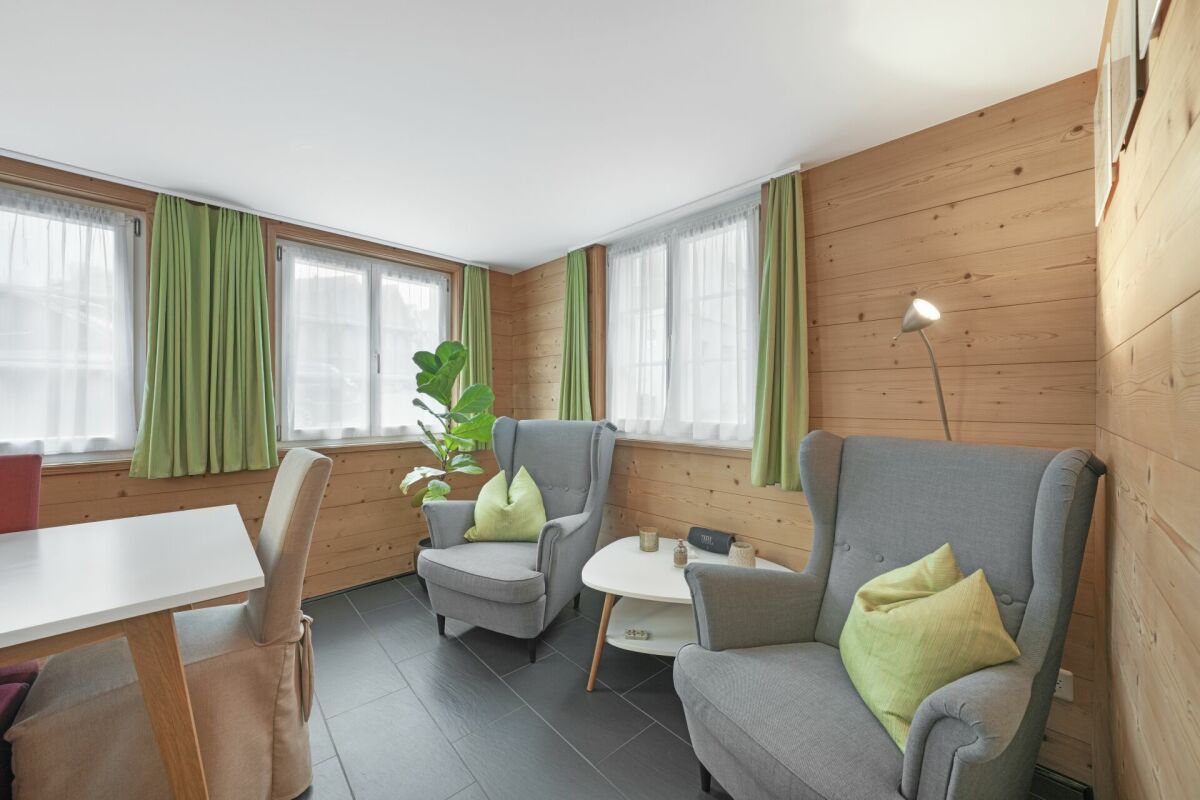 Gemütlicher Wohnraum mit Holzverkleidung und Sesseln