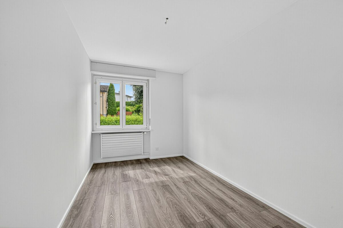 Leerer heller Raum mit Fenster und Holzoptik-Boden