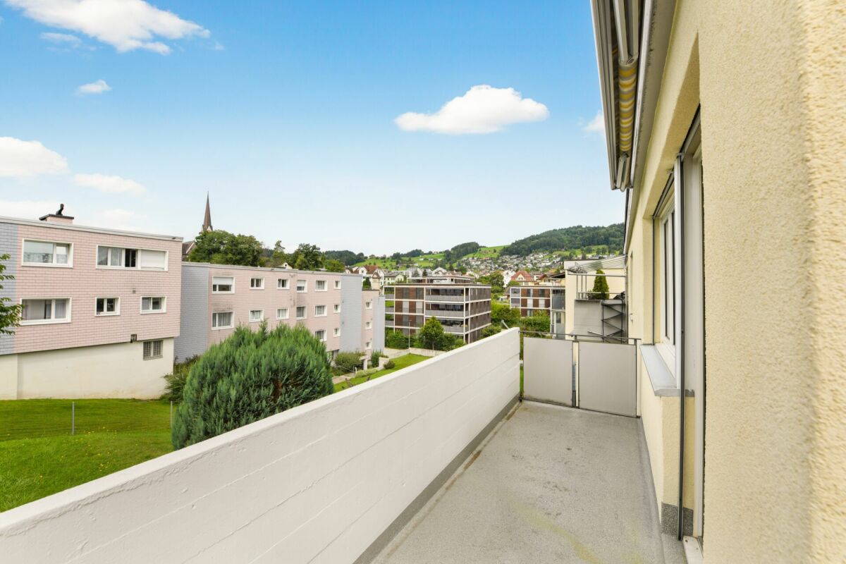Balkon mit Ausblick auf Wohnanlage und Hügel
