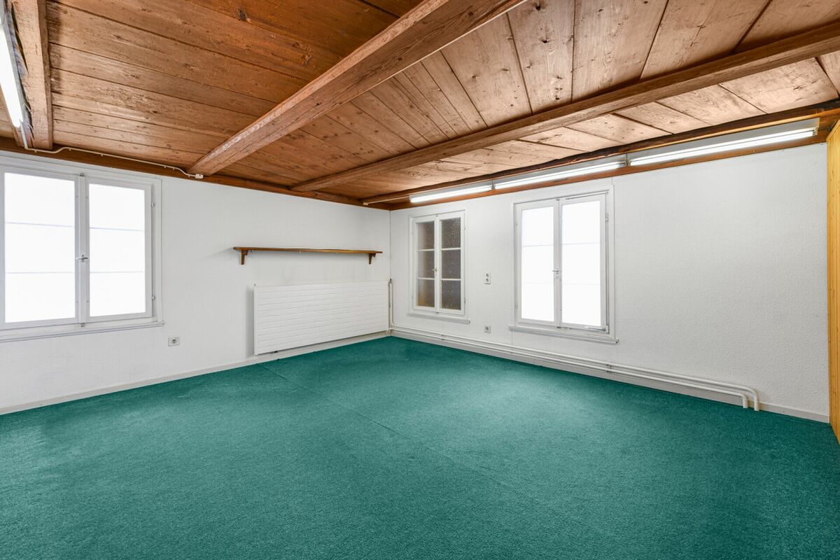 Leerer Raum mit Holzdecke und grünem Teppich