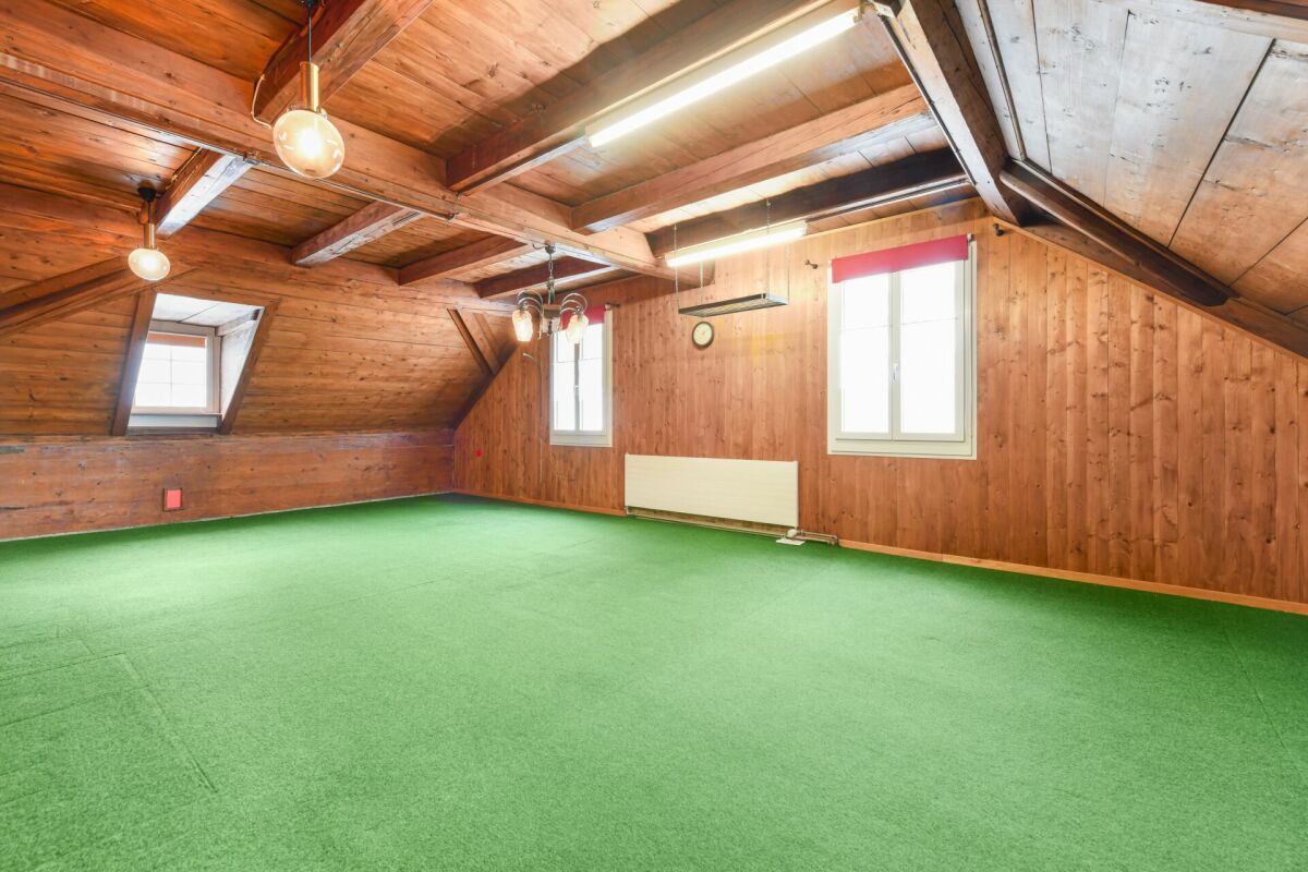 Dachgeschossraum mit Holzverkleidung und grünem Teppichboden