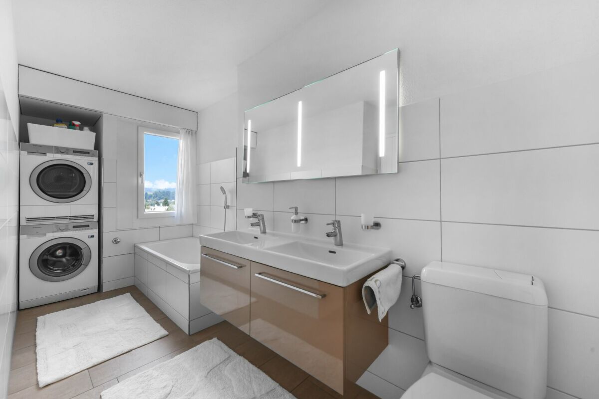 Modernes Badezimmer mit Waschtisch, Badewanne und Waschmaschinenbereich