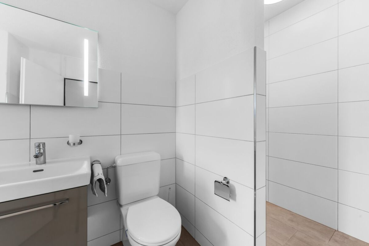 Gäste-WC mit weißen Fliesen und Waschtisch