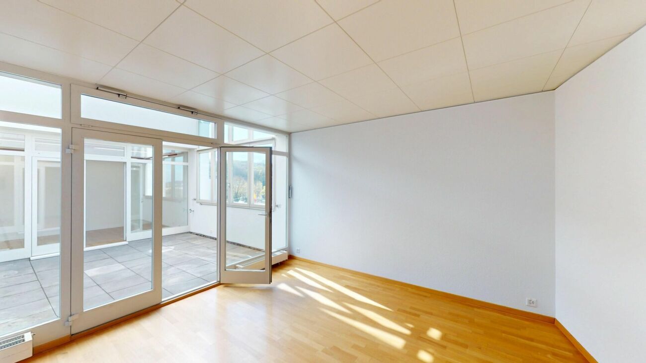 Heller leerer Raum mit Glasfront zum Innenhof