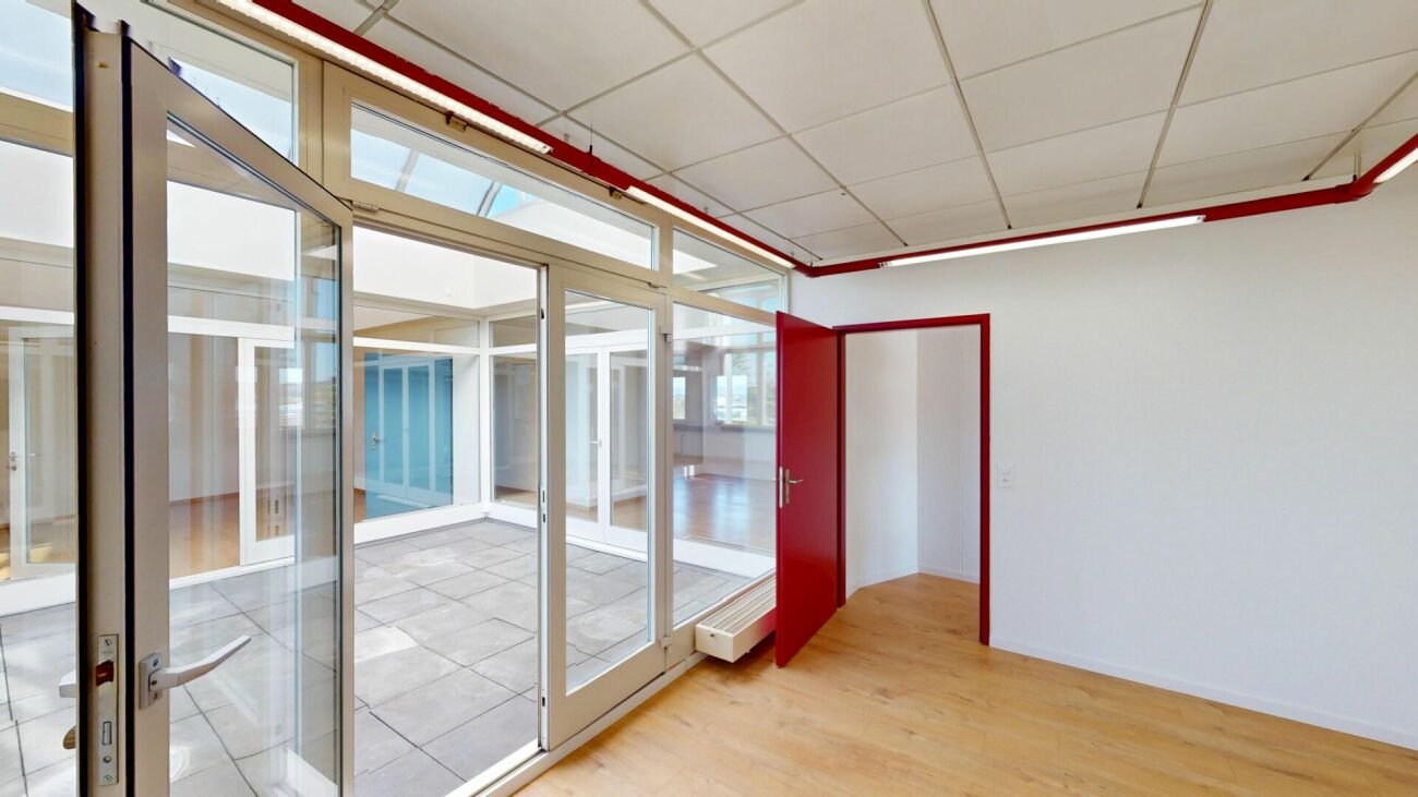 Innenraum mit Glaswänden und roter Tür