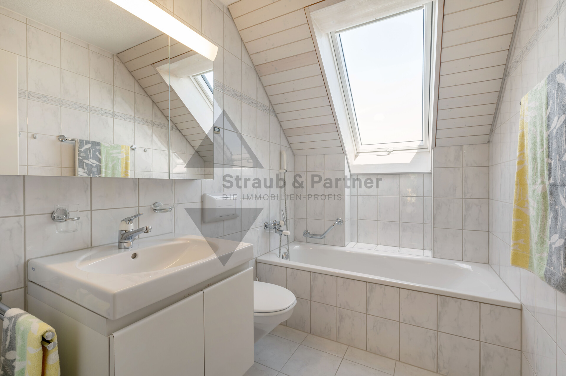 Helles Dachgeschossbad mit Badewanne und Waschbecken