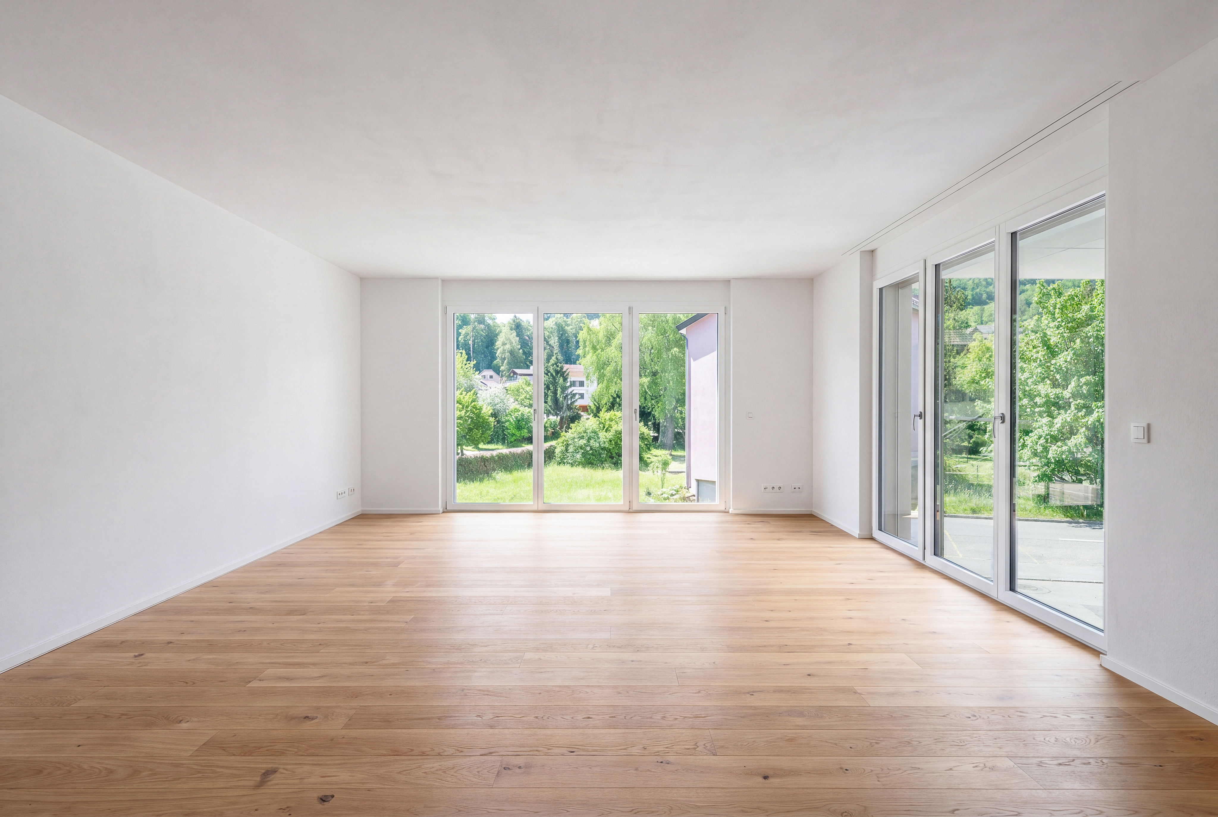 Heller leerer Wohnraum mit großen Fenstern