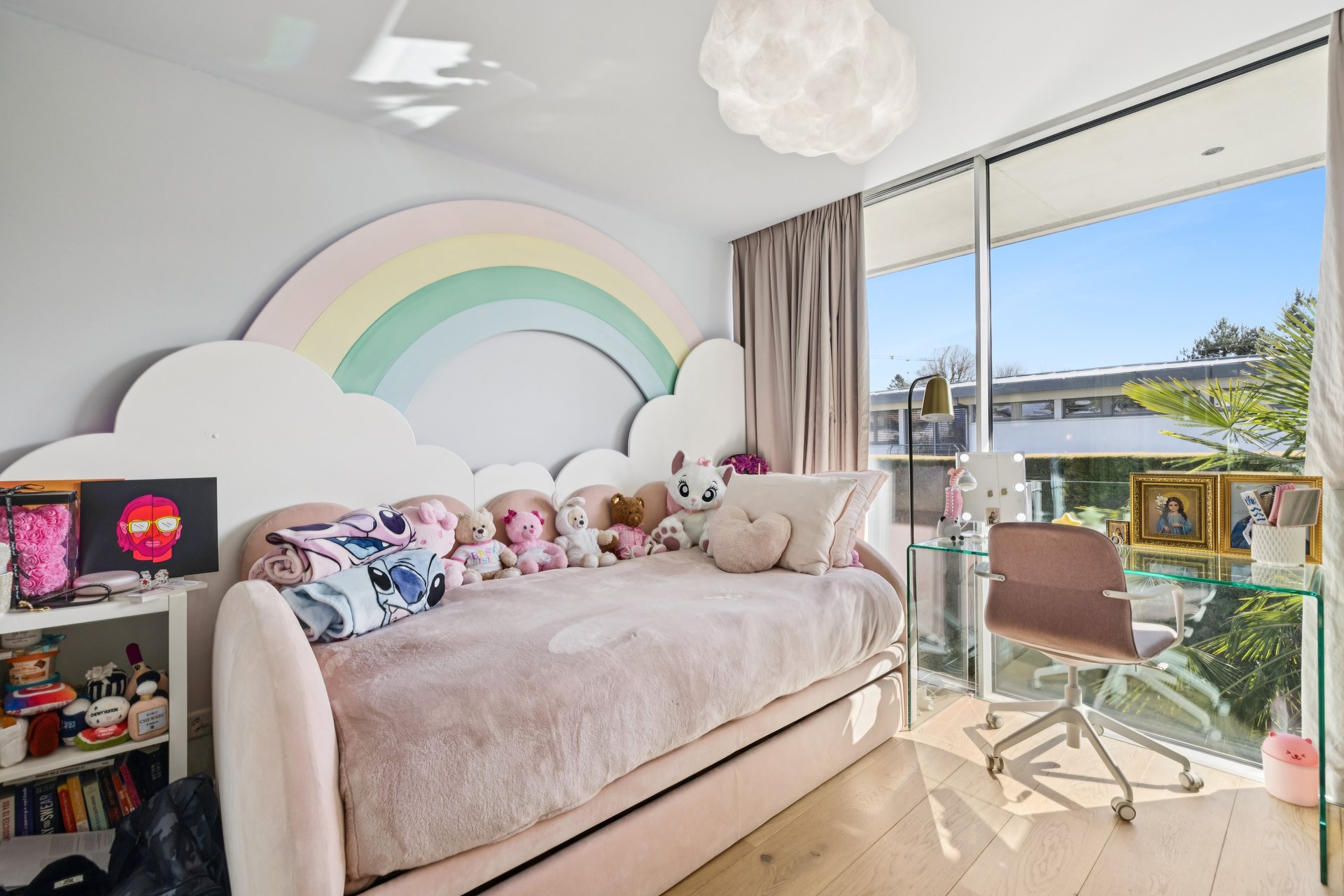 Helles Kinderzimmer mit Regenbogenwand und Schreibtisch am Fenster