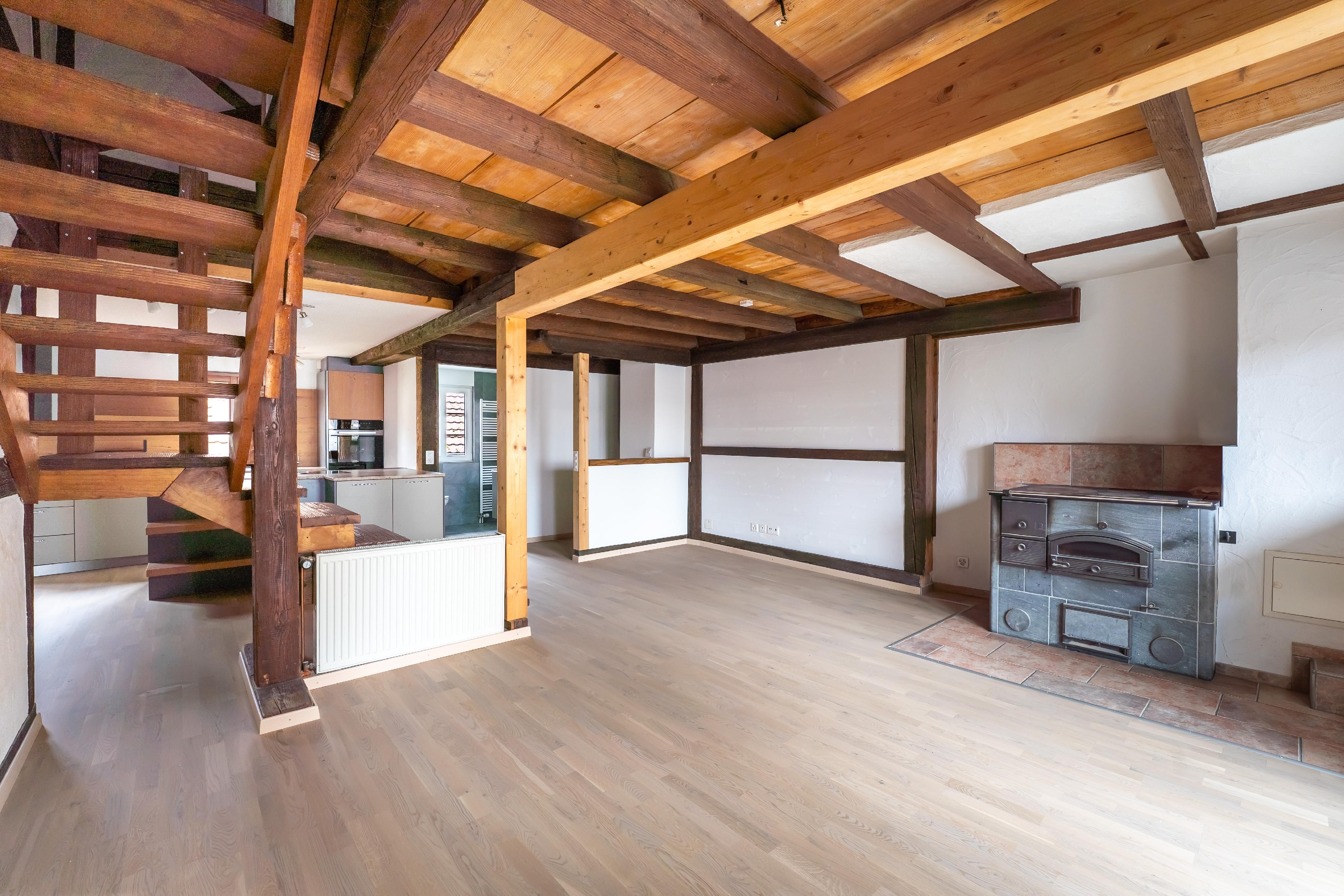 Wohnraum mit sichtbarem Holzbalkenwerk und Ofen