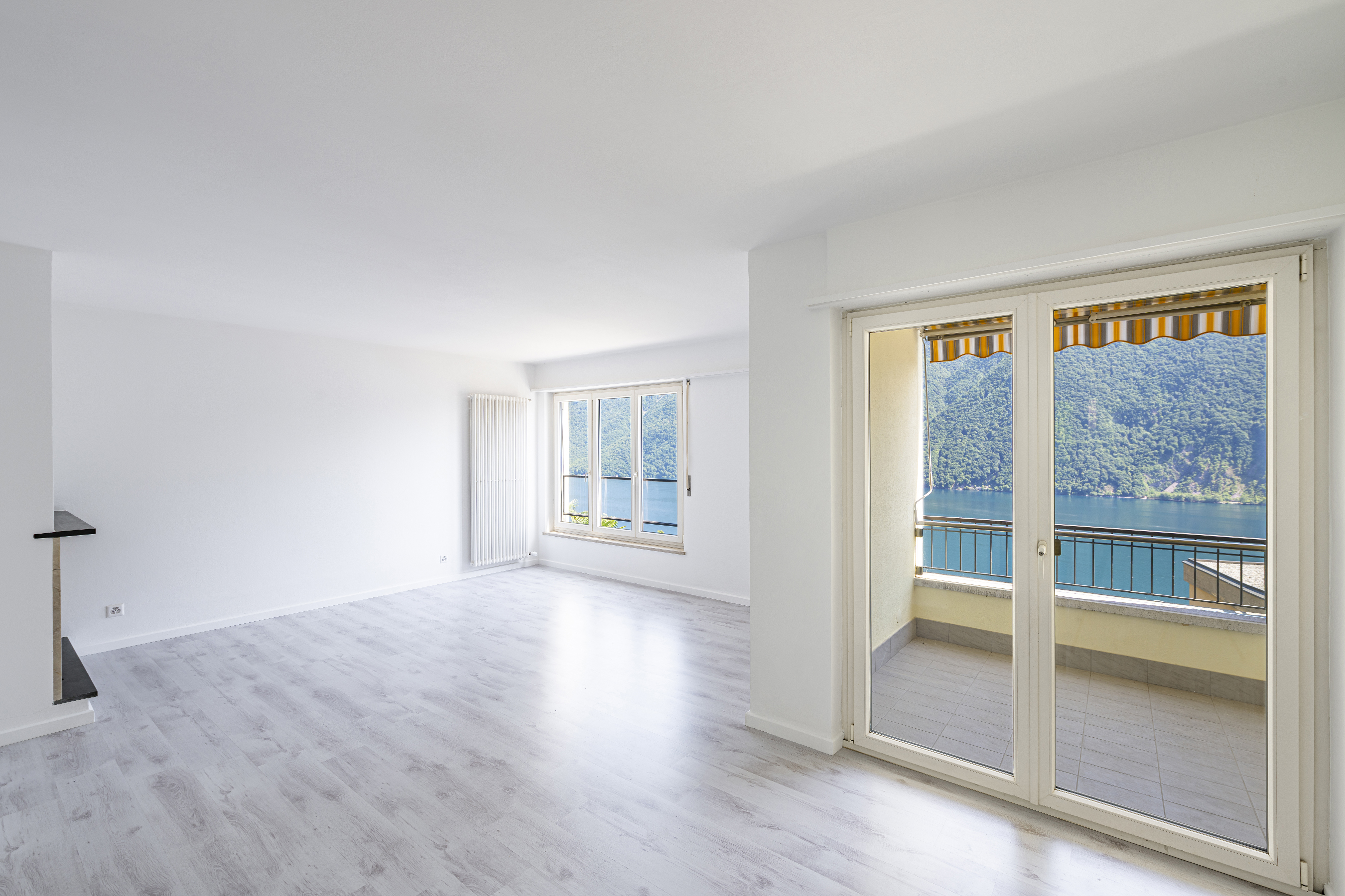 Heller leerer Wohnraum mit Balkonblick auf See und Berge