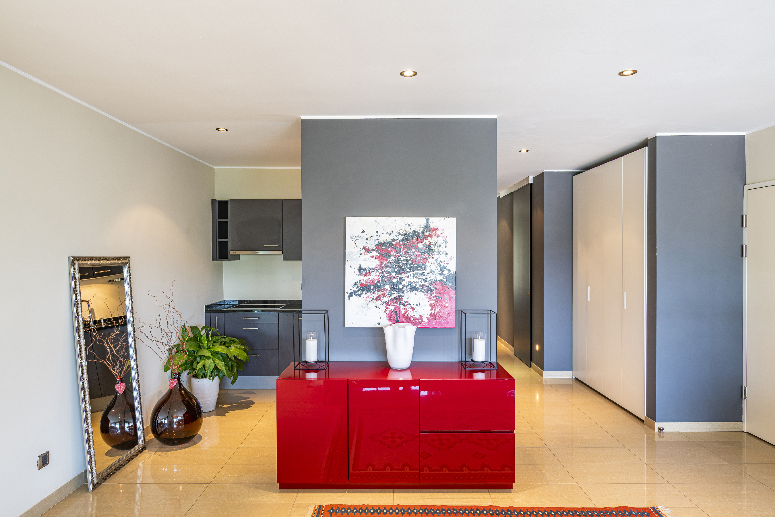 Modern eingerichteter Wohnbereich mit Küchenzeile und glänzendem Sideboard