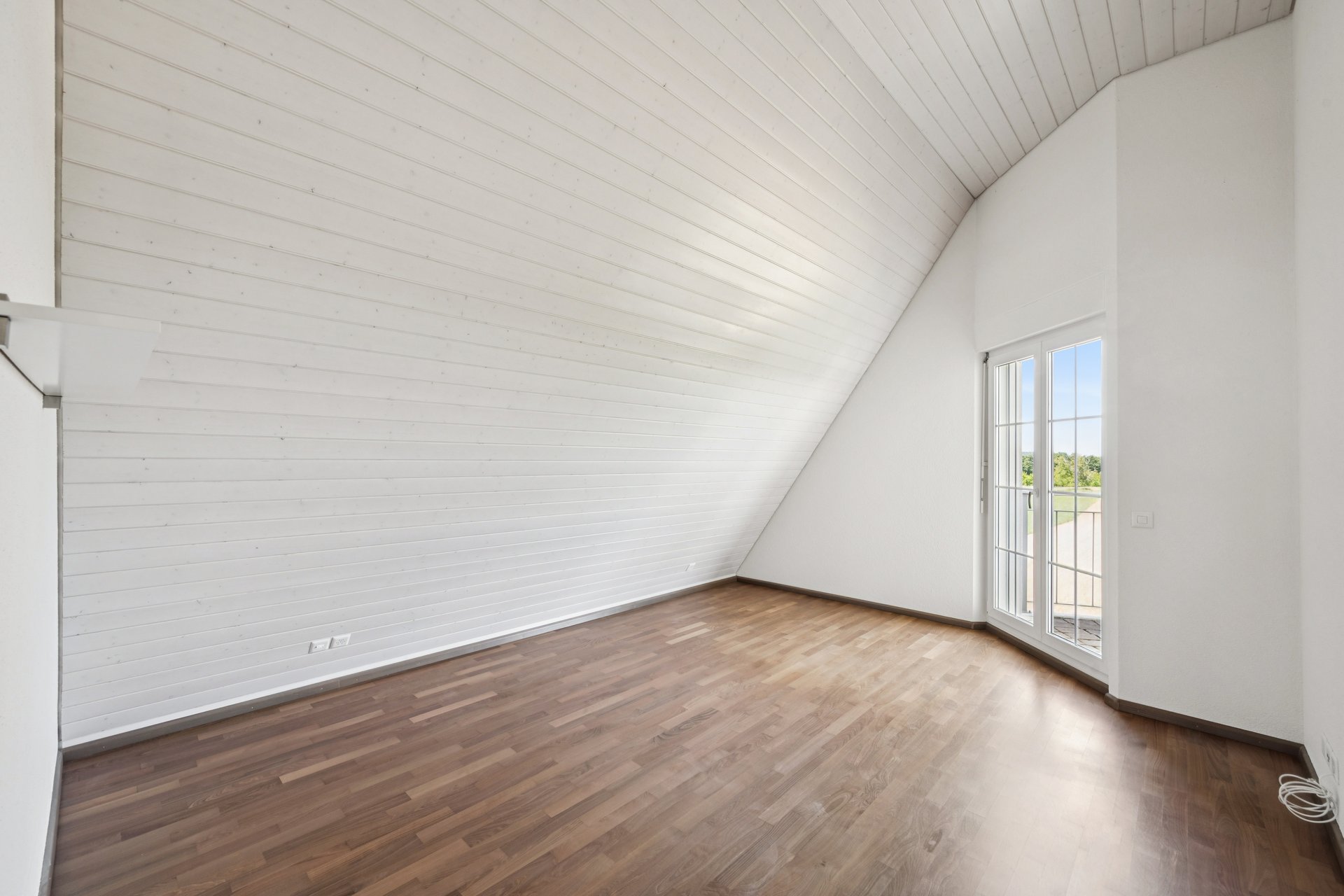 Helles Dachzimmer mit Holzdecke und Balkontür