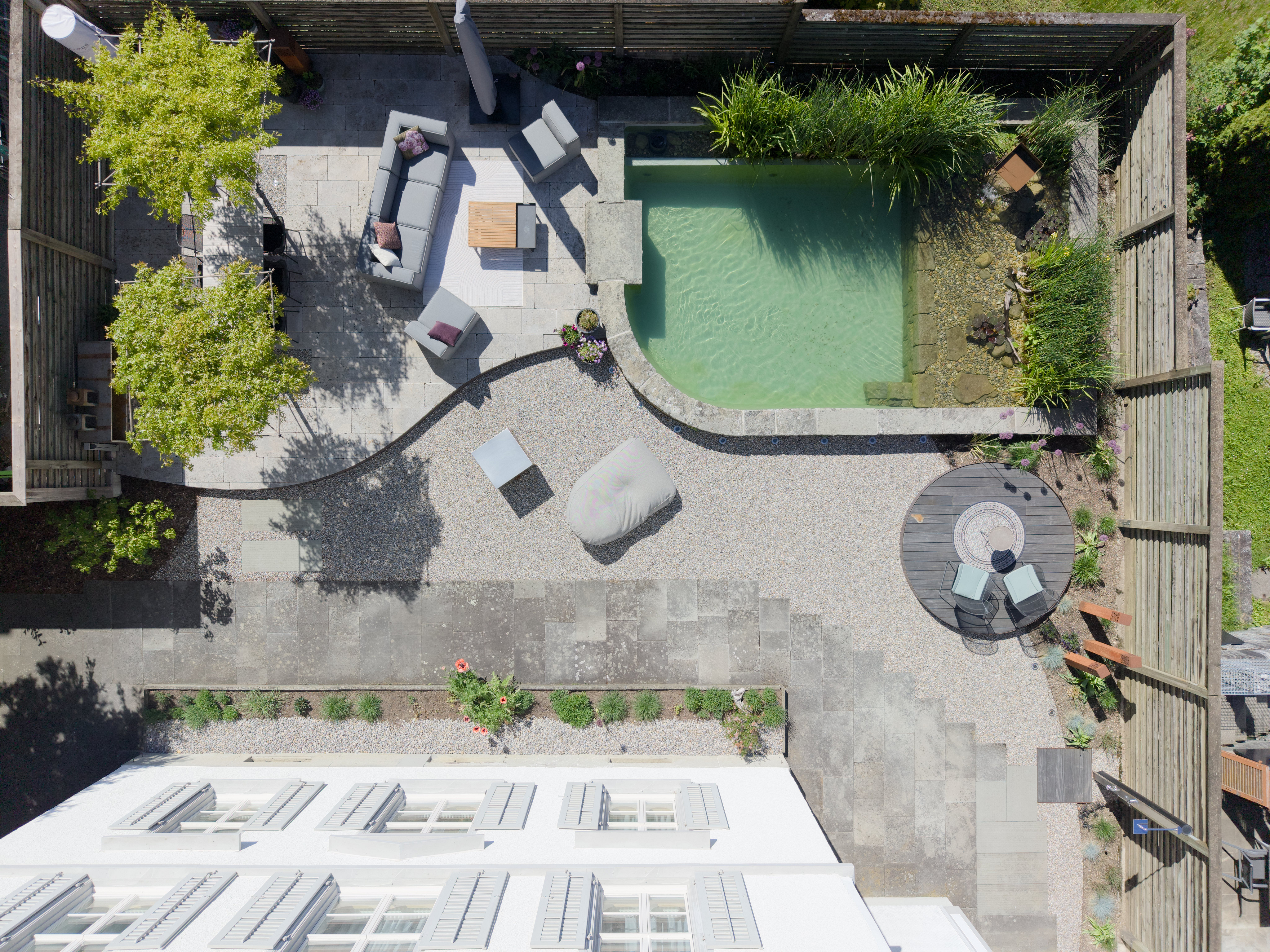 Drohnenaufnahme eines gestalteten Gartens mit Pool und Terrassen