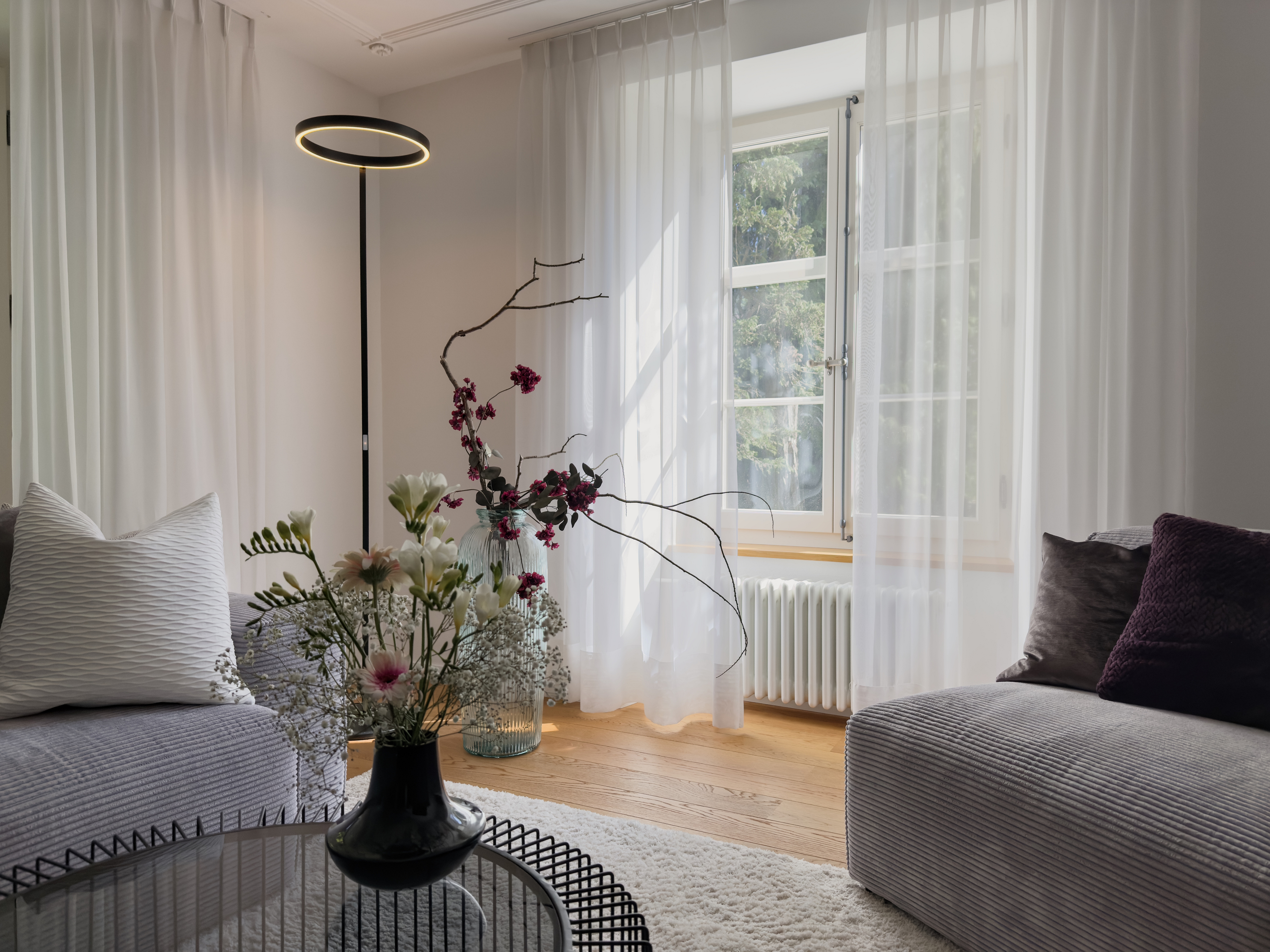 Helles, stilvolles Wohnzimmer mit Fenster und Blumen