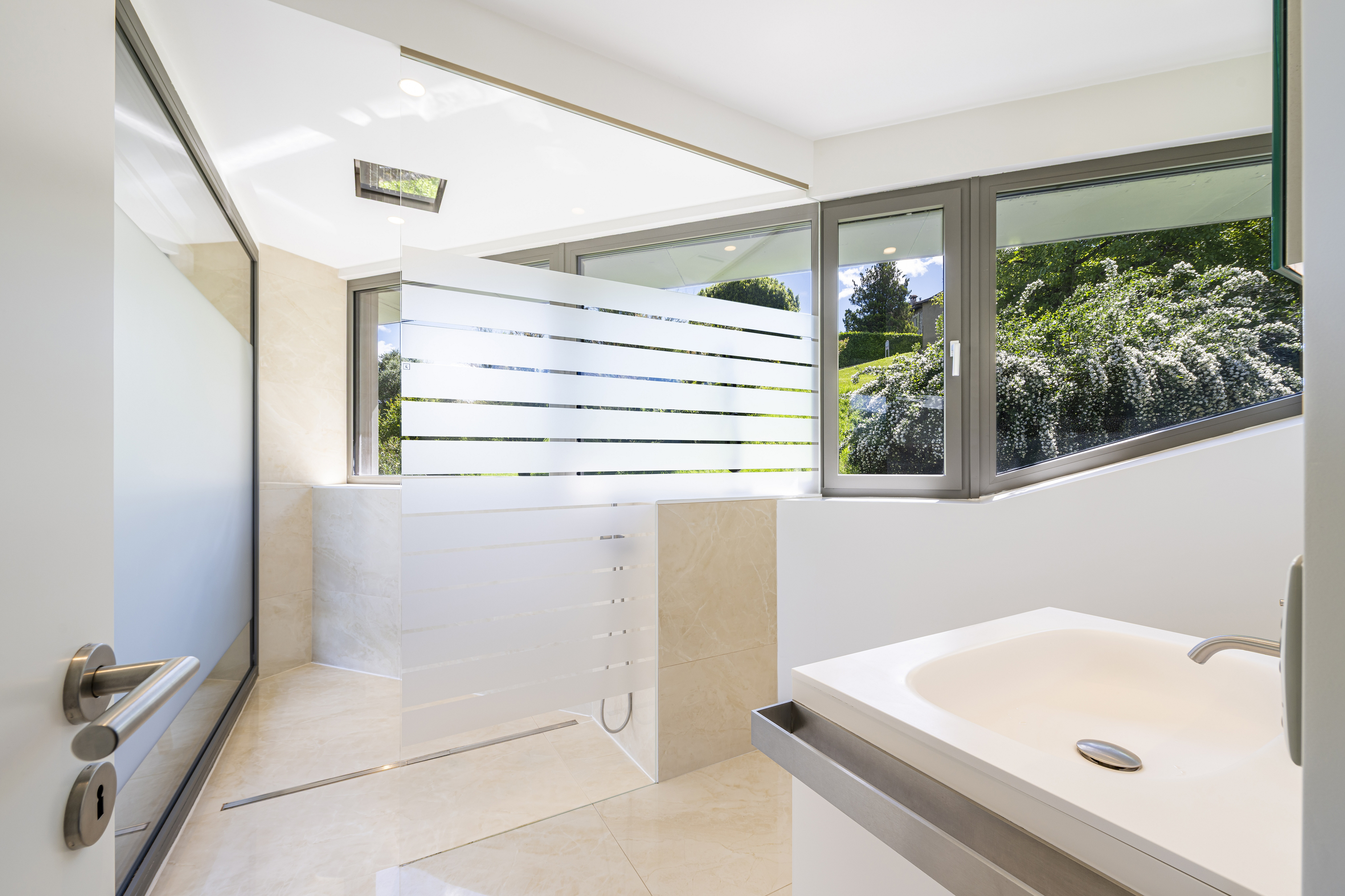 Helles, modernes Badezimmer mit Badewanne und Blick ins Grüne