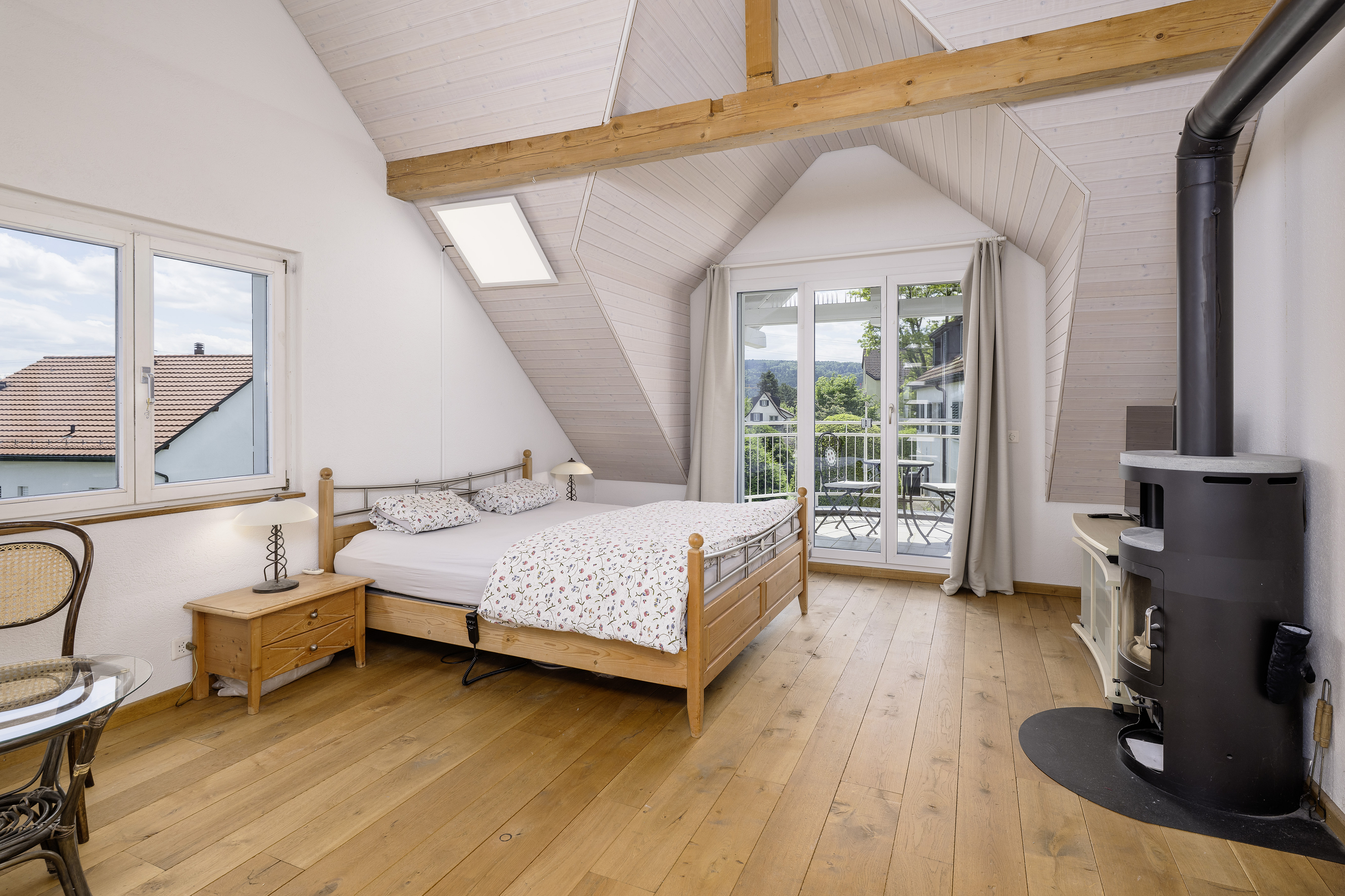 Dachgeschoss-Schlafzimmer mit Balkon und Holzofen