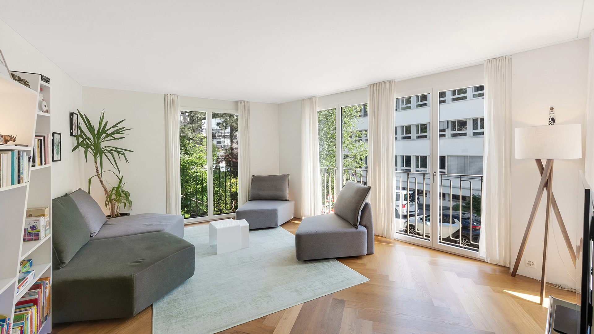 Helles Wohnzimmer mit großen Fenstern und Balkonblick