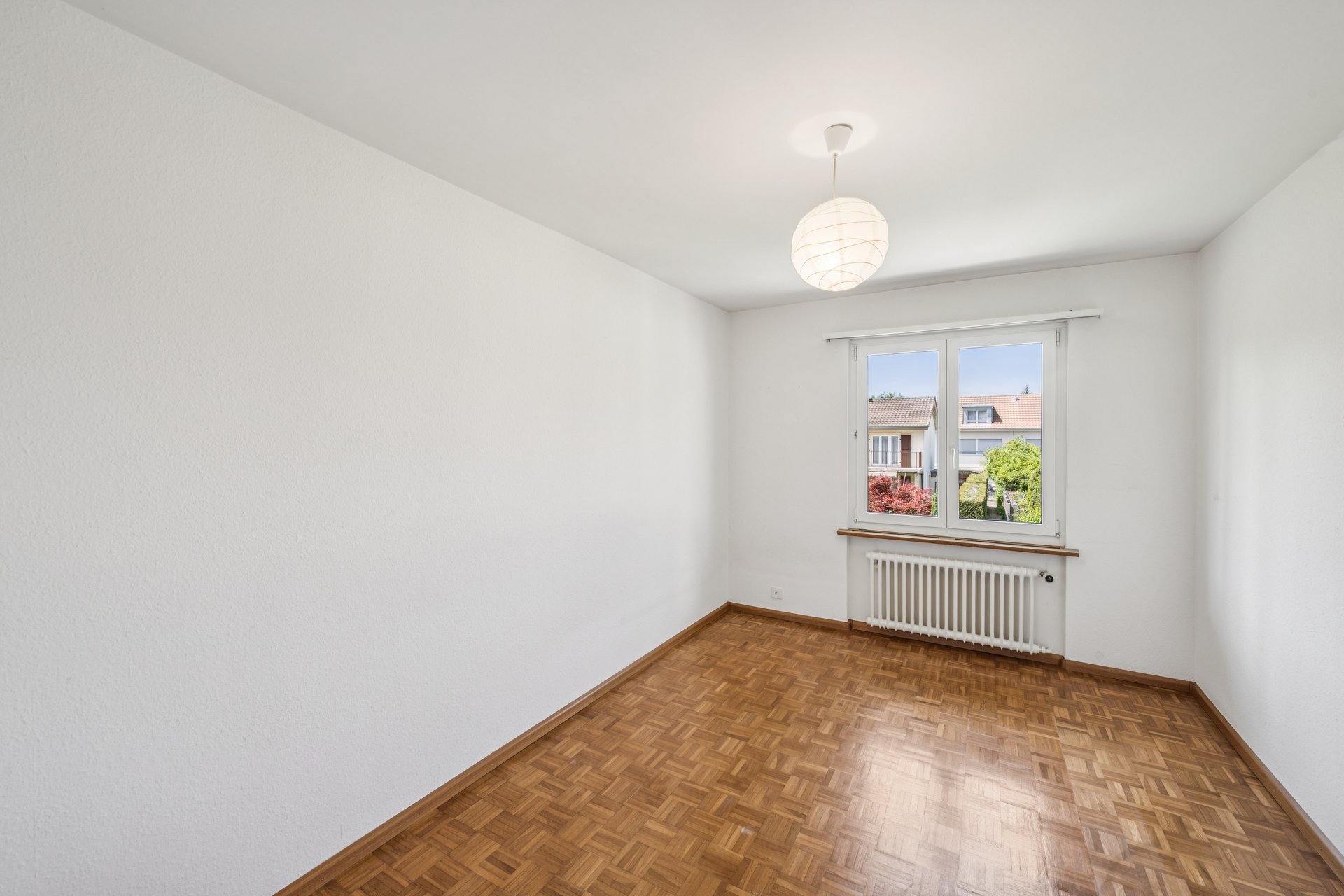 Heller leerer Raum mit Parkettboden und Fenster