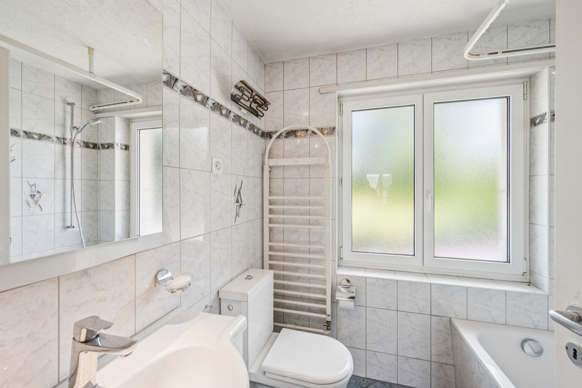 Helles, gefliestes Badezimmer mit Fenster