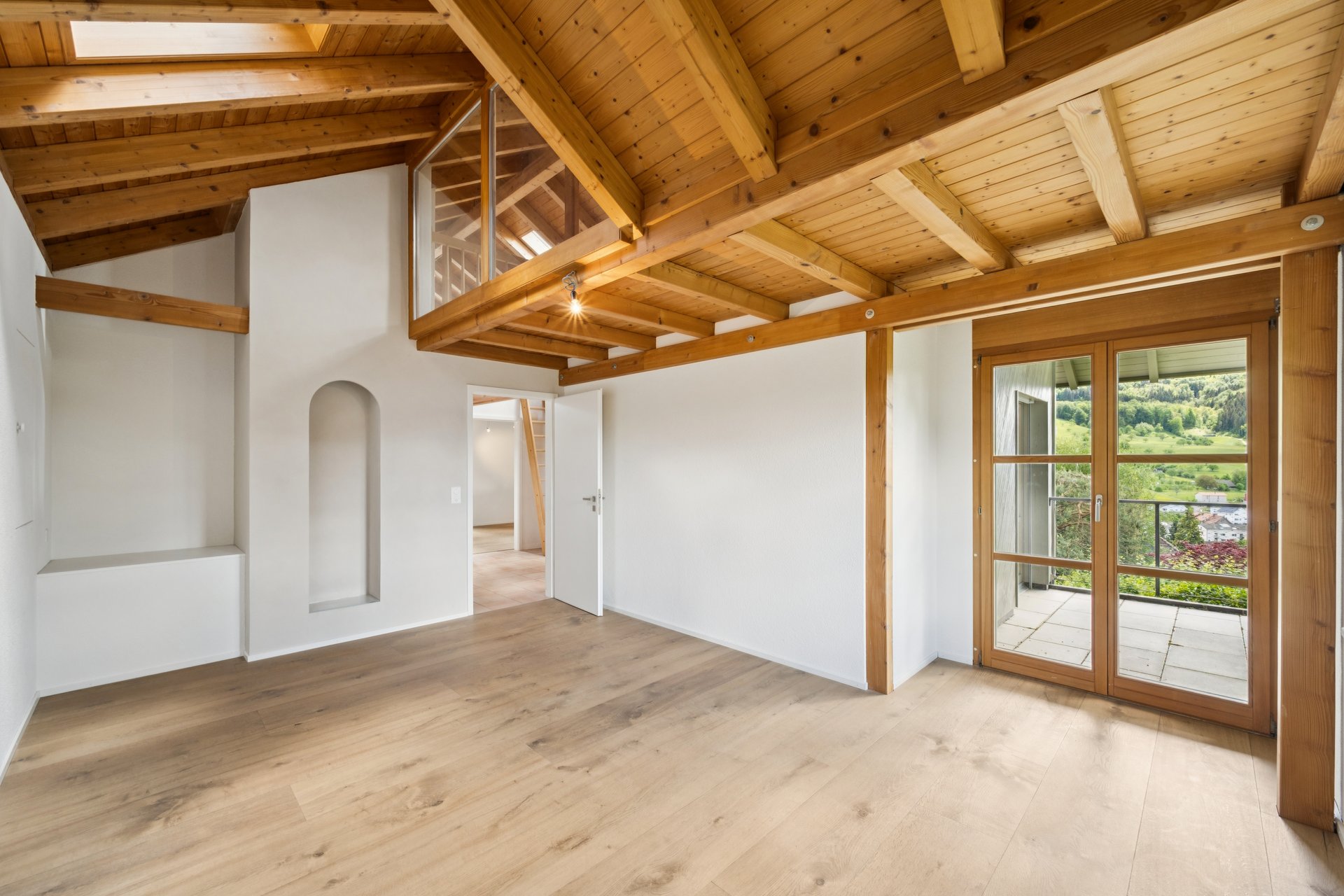 Heller Dachgeschossraum mit Holzdecke und Blick ins Grüne