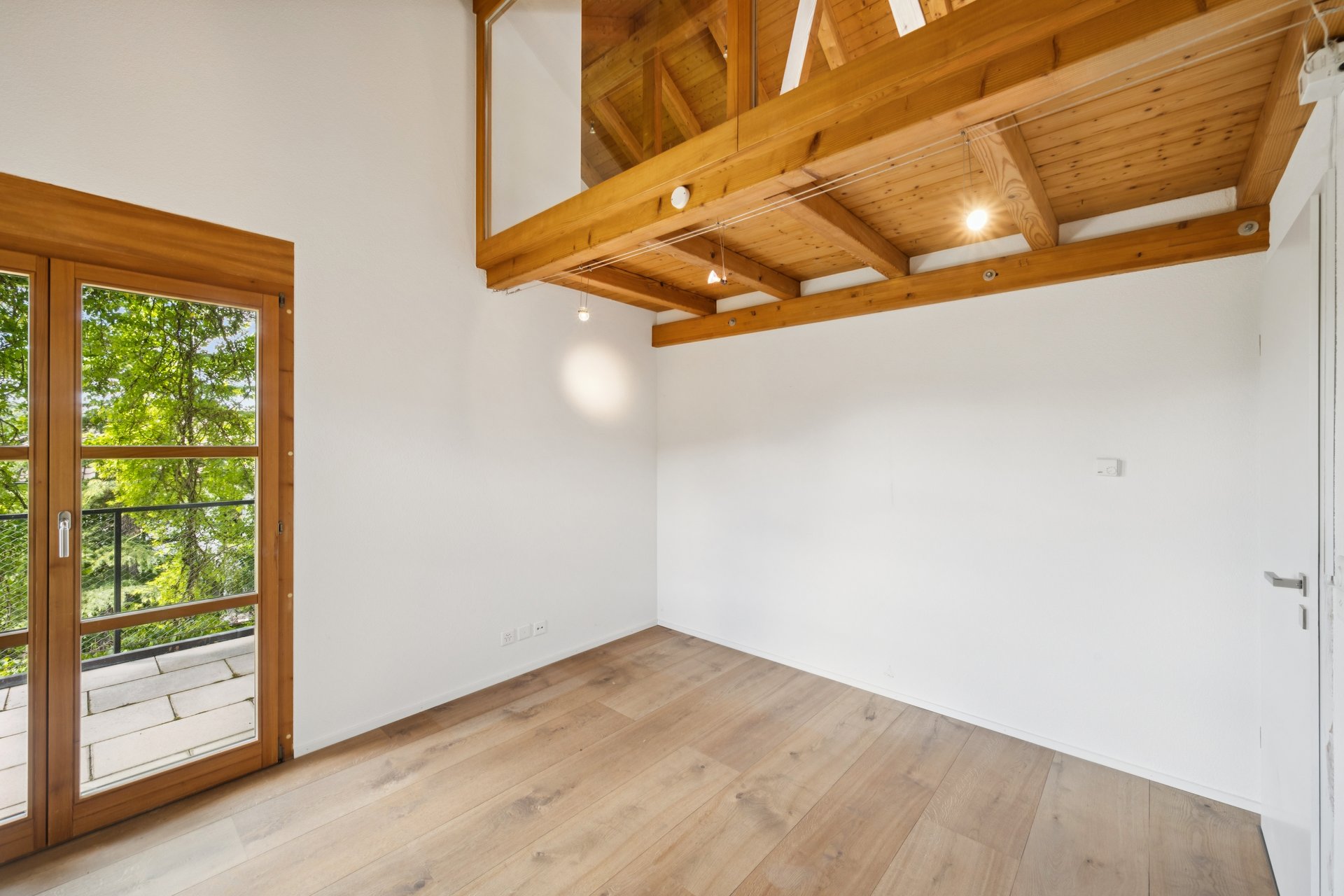Heller leerer Raum mit Holzdecke und Balkonblick