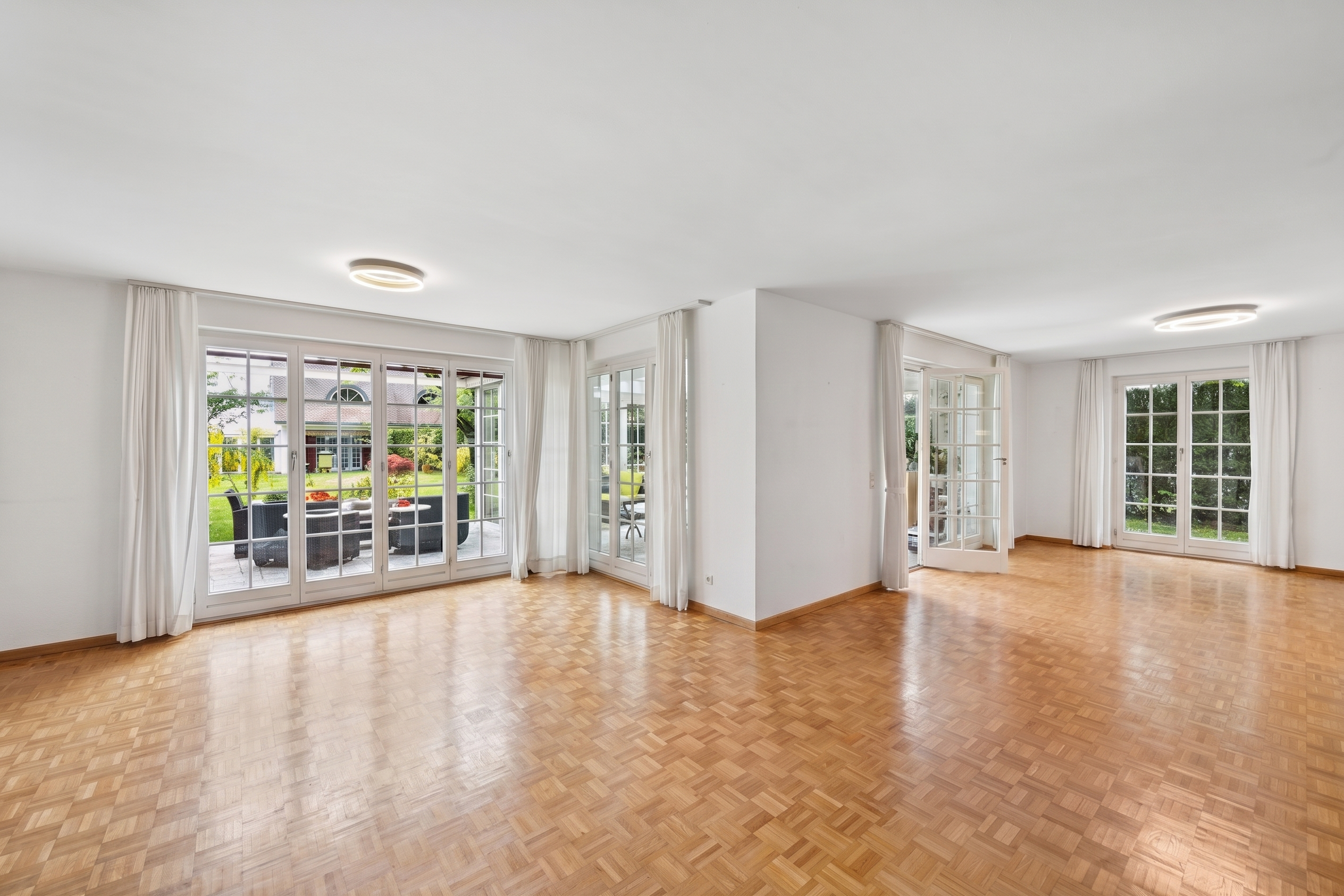 Heller Wohnraum mit Parkett und großen Fenstern