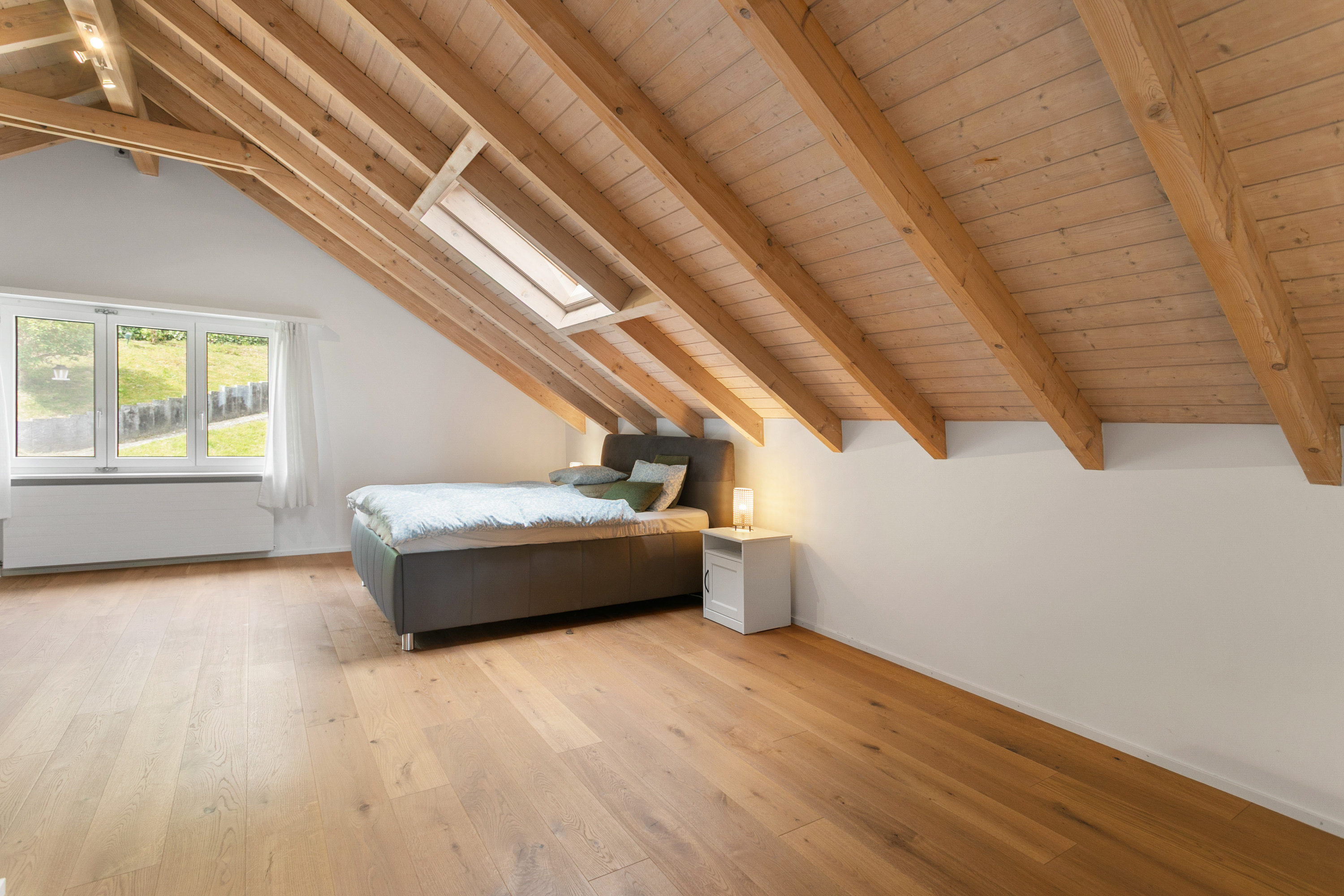 Dachgeschoss-Schlafzimmer mit sichtbaren Holzbalken