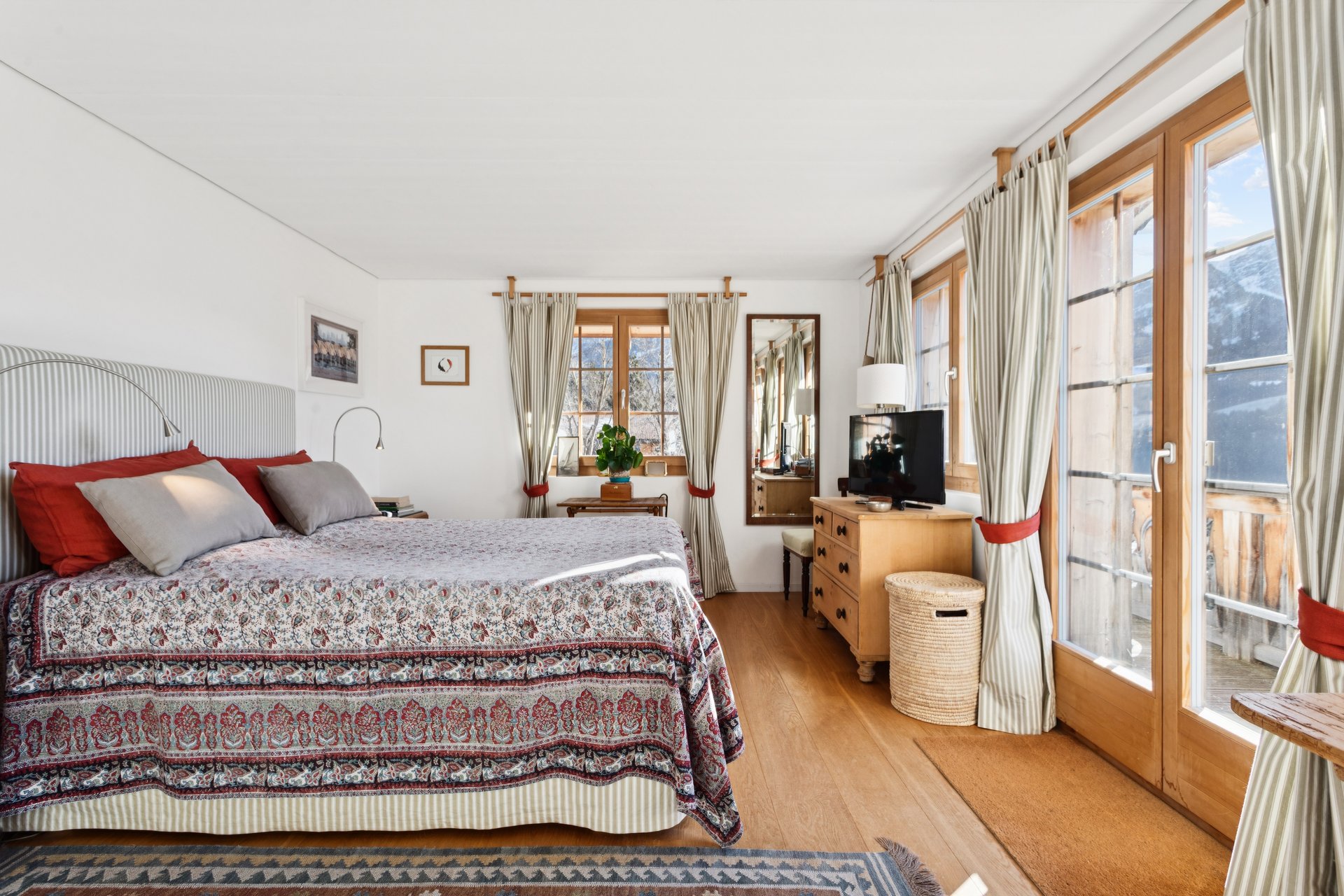 Helles Schlafzimmer mit Holzfenstern und Blick nach draußen