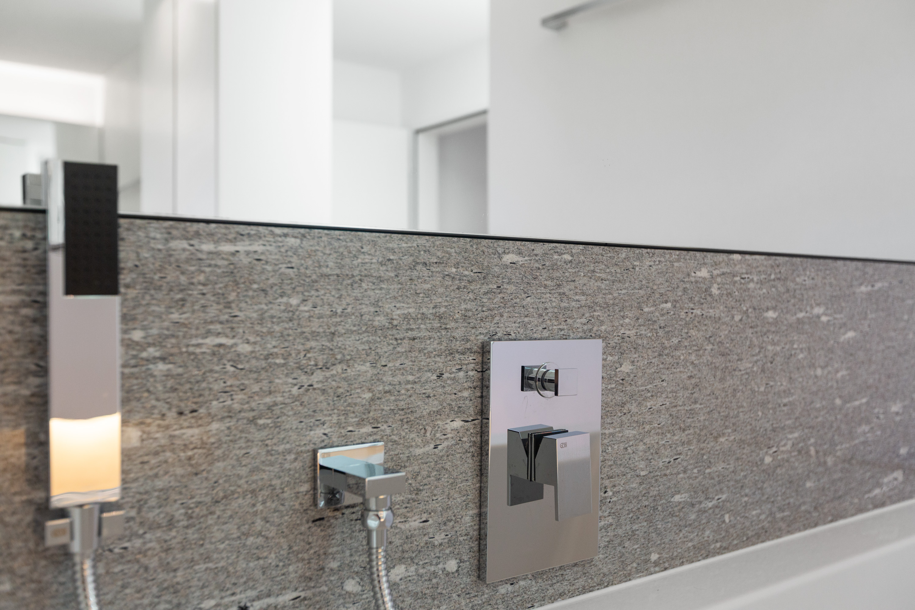 Modernes Badezimmerdetail mit Natursteinwand und Armaturen