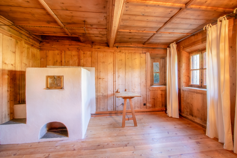 Rustikaler Raum mit Holzverkleidung und weißem Ofen