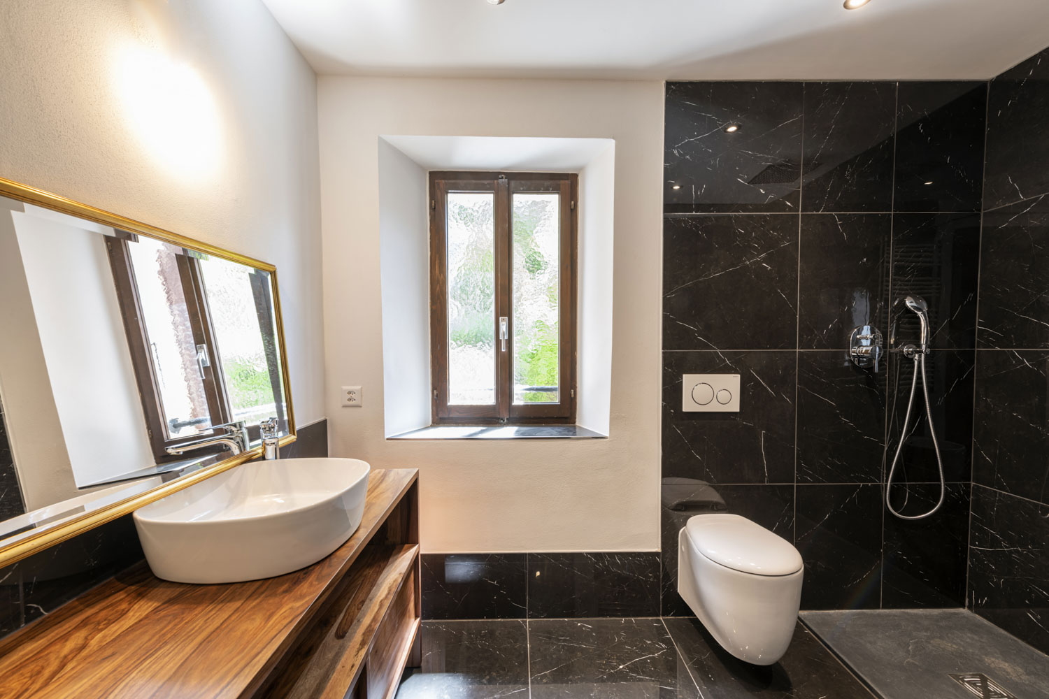 Modernes Badezimmer mit schwarzer Natursteinoptik und Holzkonsole