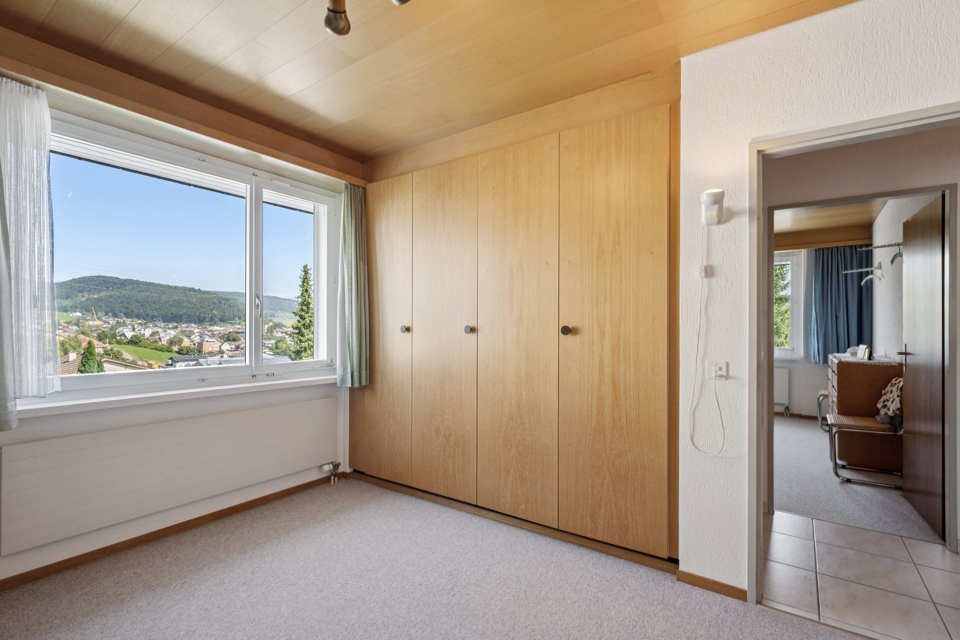 Helles Schlafzimmer mit Einbauschrank und Ausblick ins Tal