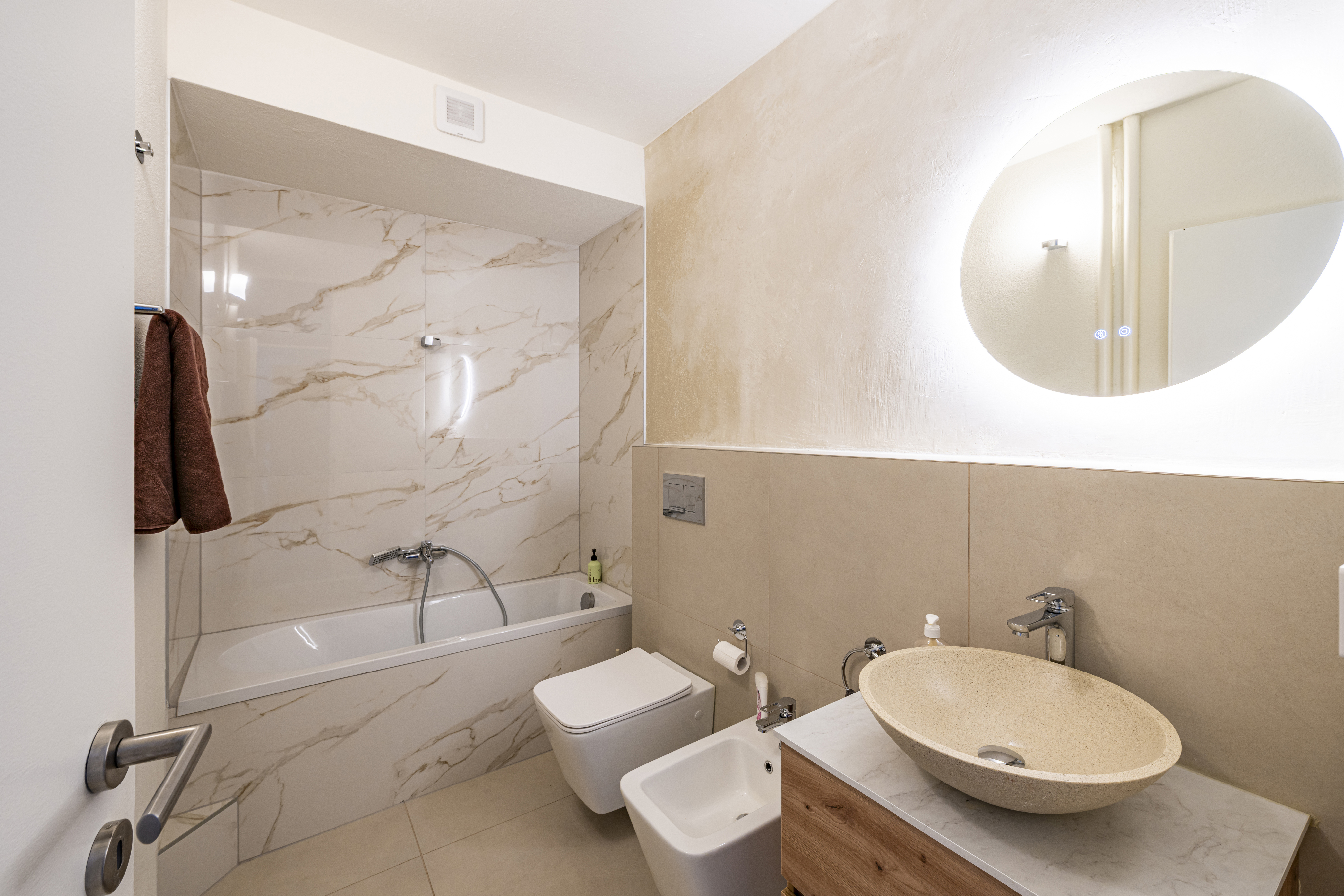 Modernes Bad mit Wanne und Natursteinwaschbecken