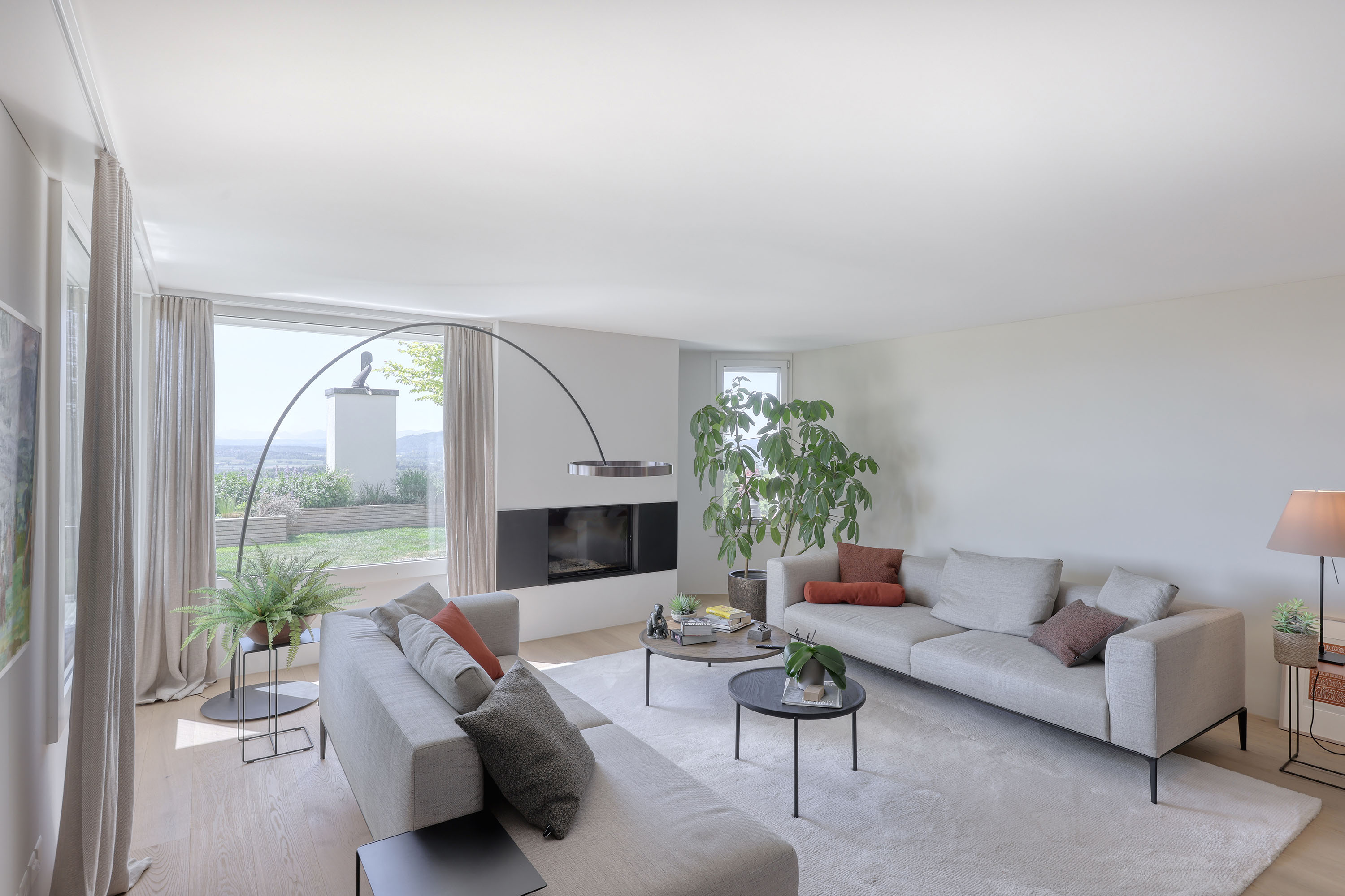 Heller moderner Wohnraum mit Kamin und Blick ins Grüne