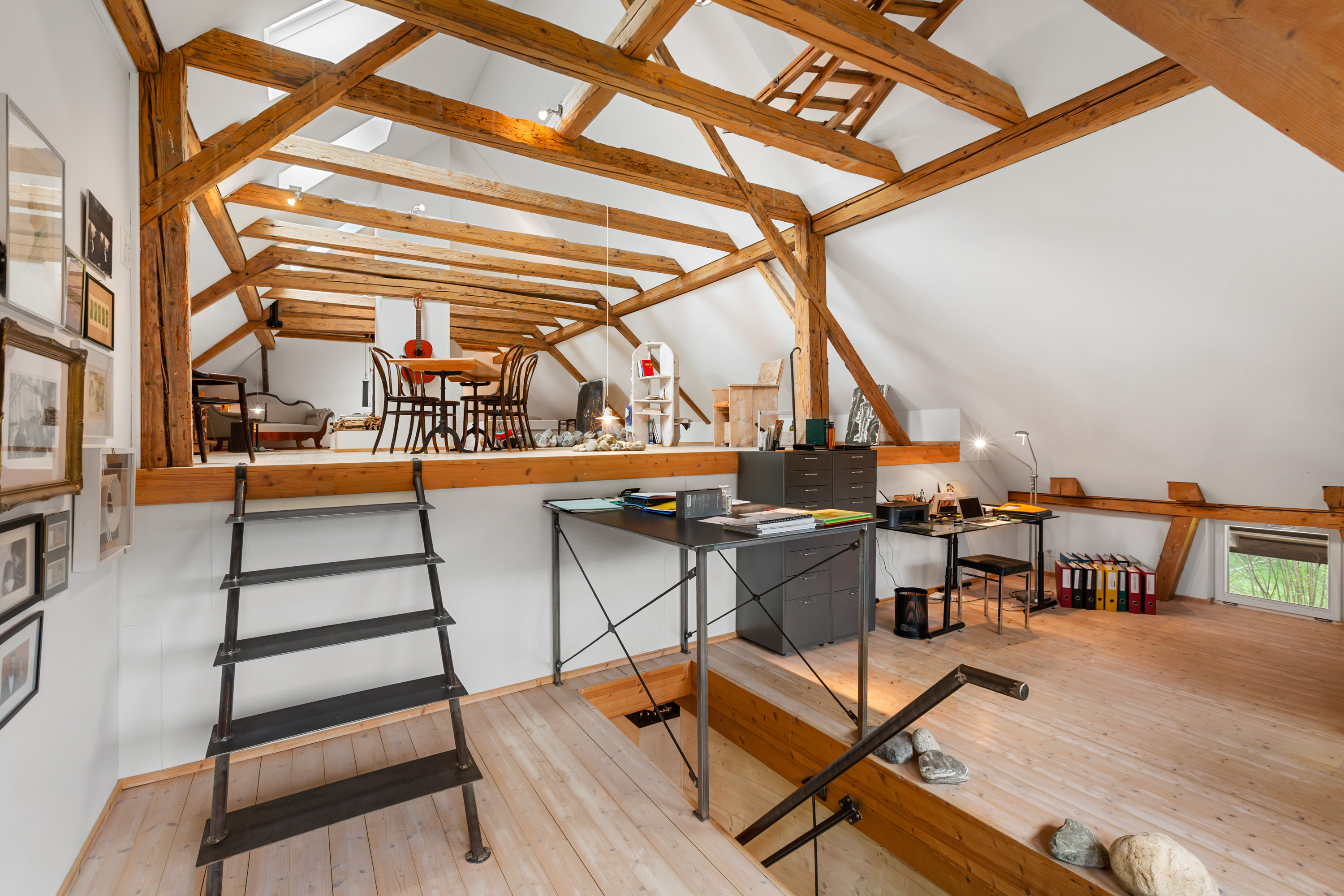 Helles Atelier mit sichtbaren Holzbalken und Galerie