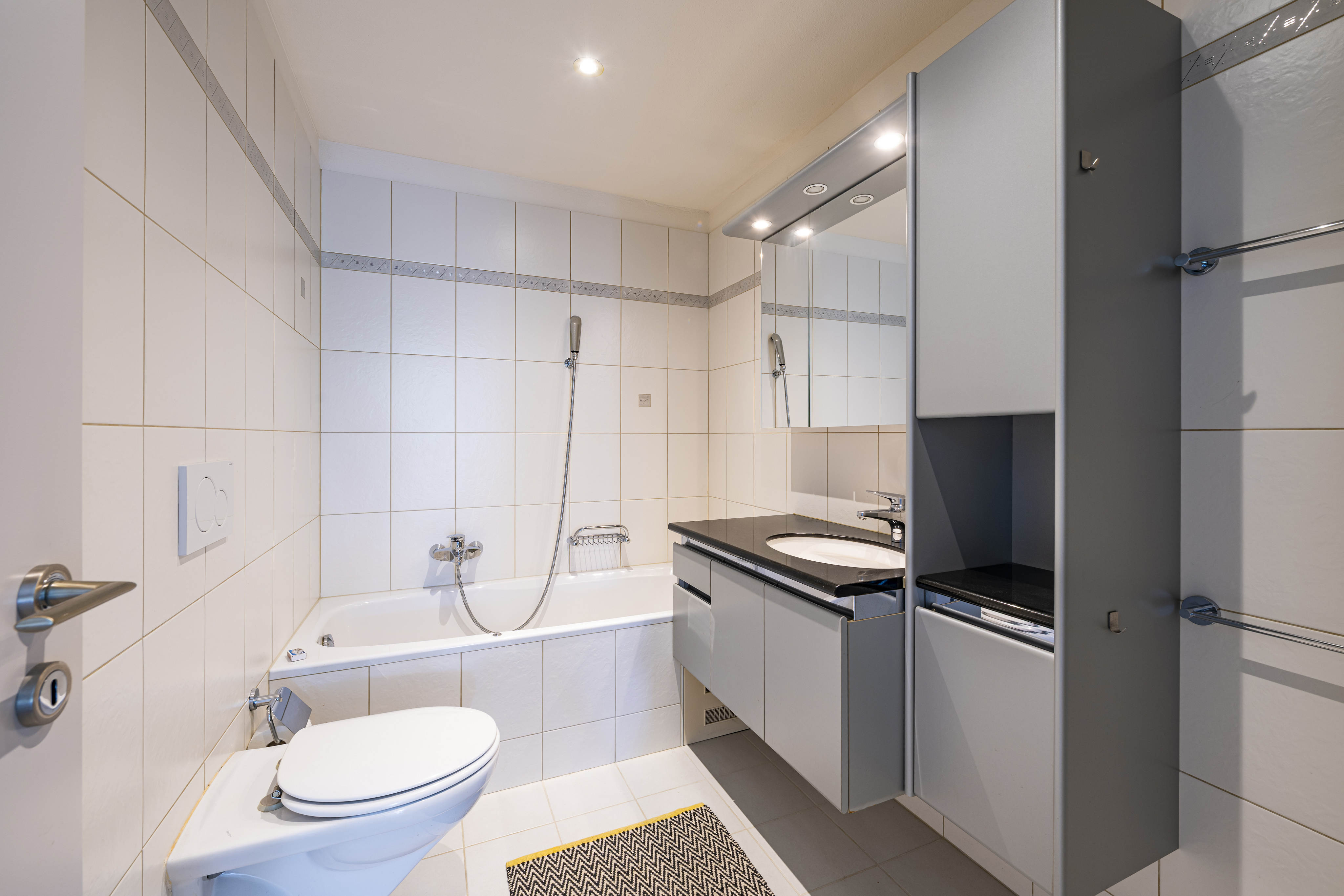 Kleines, modernes Badezimmer mit Badewanne und WC