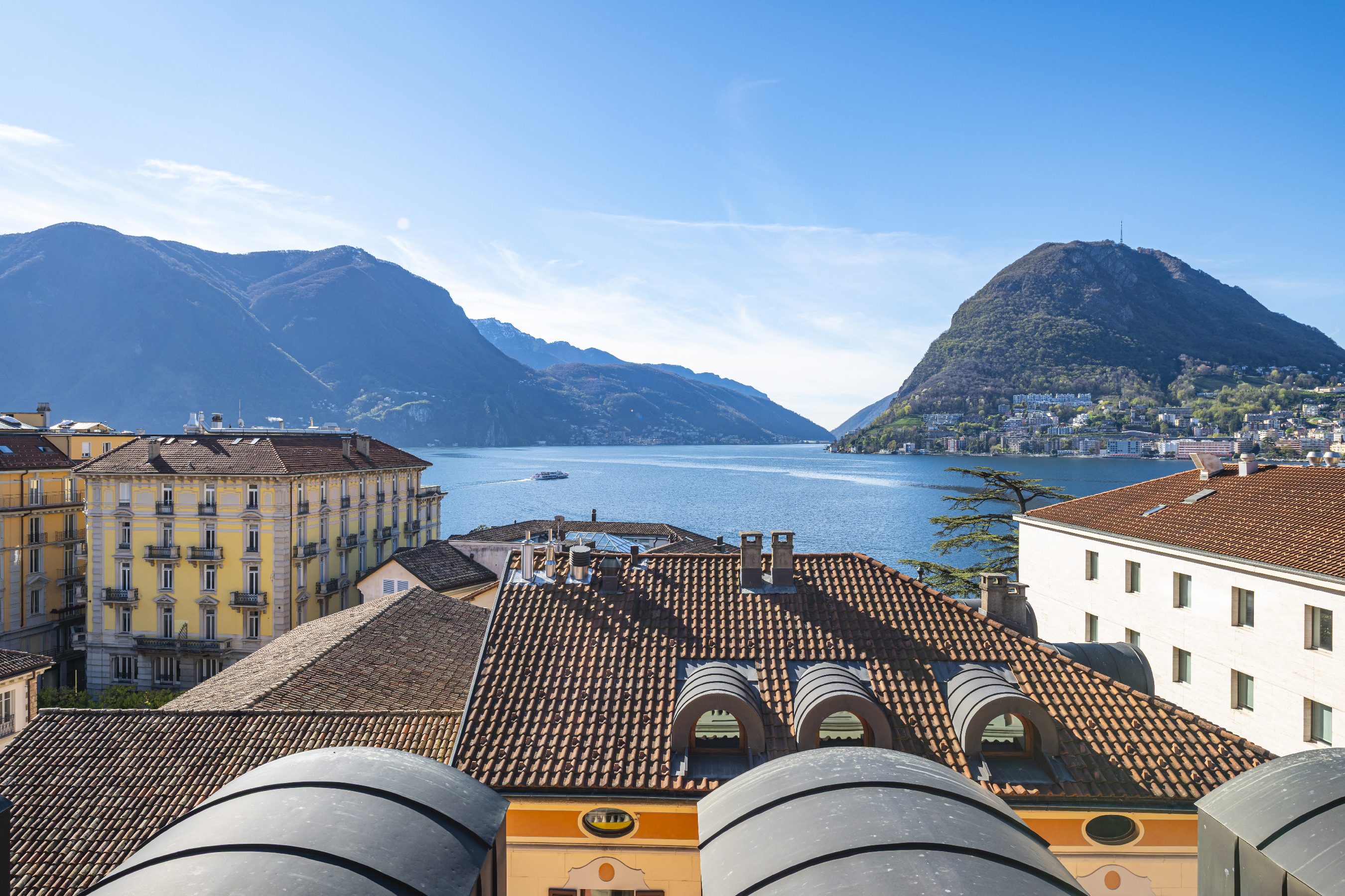 Seeblick mit Bergen und Dachlandschaft
