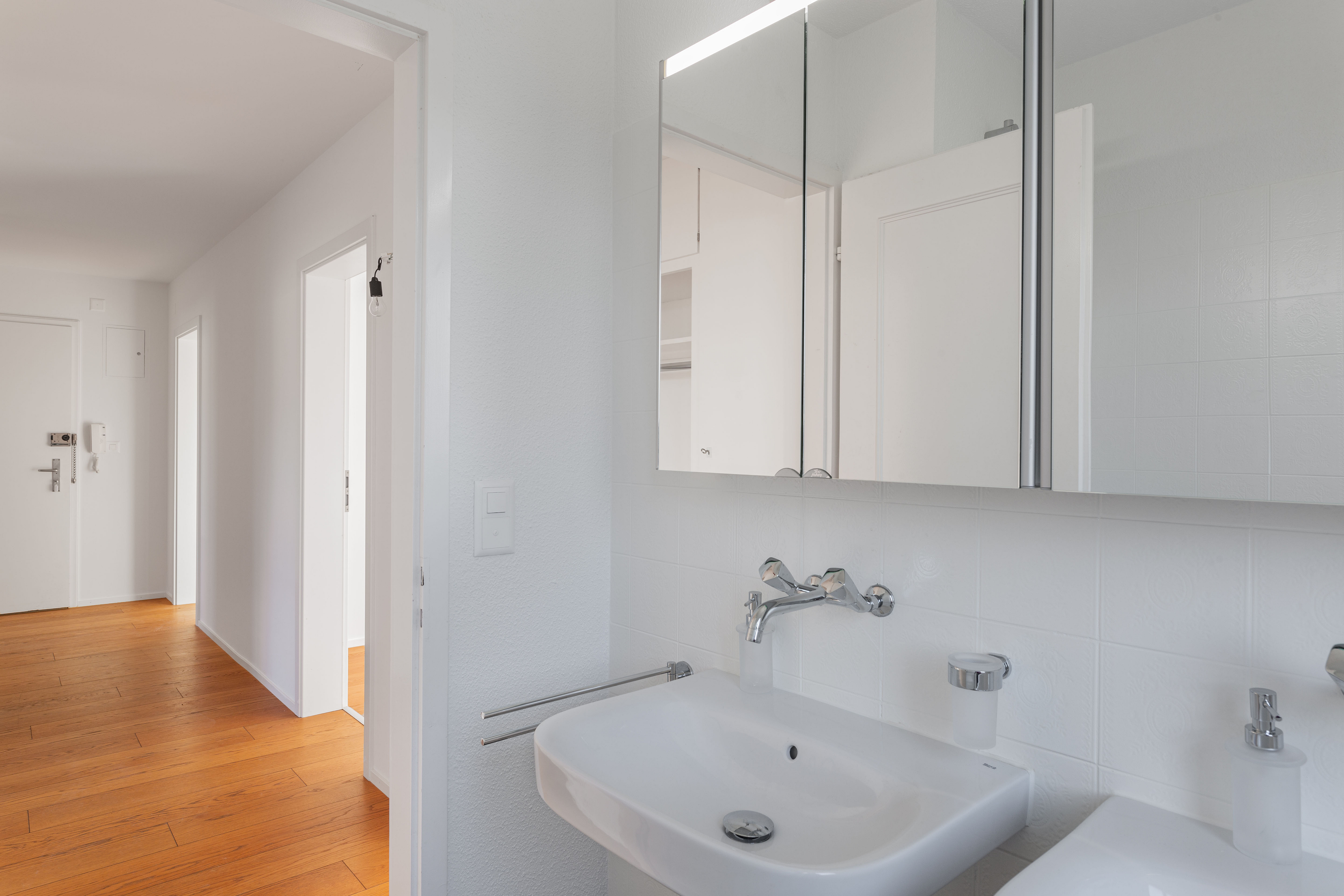 Helles Badezimmer mit Flur im Hintergrund