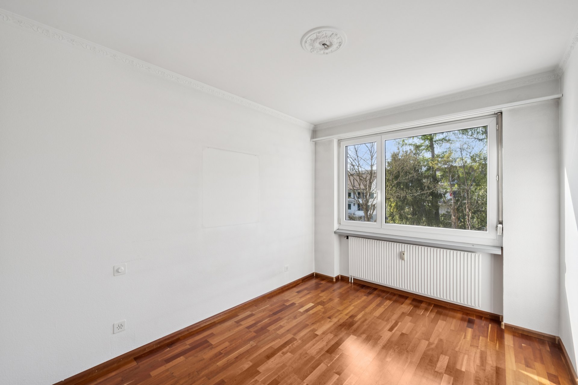 Helles leeres Zimmer mit Parkett und Fenster