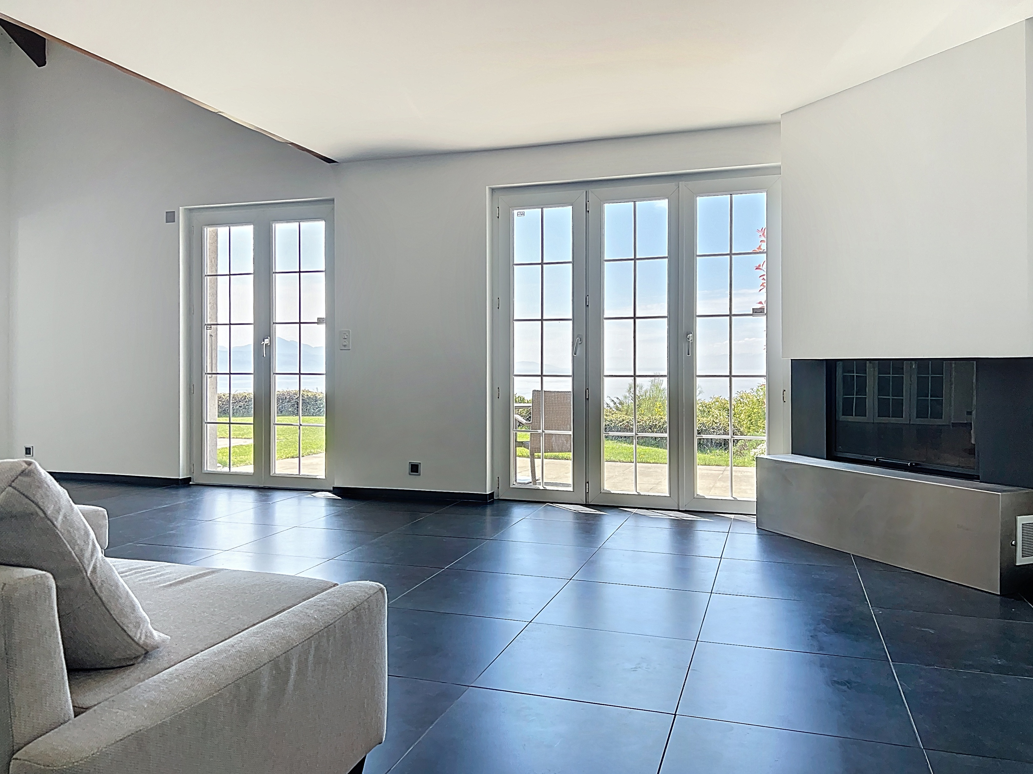 Heller Wohnraum mit großflächigen Fenstertüren und Kamin