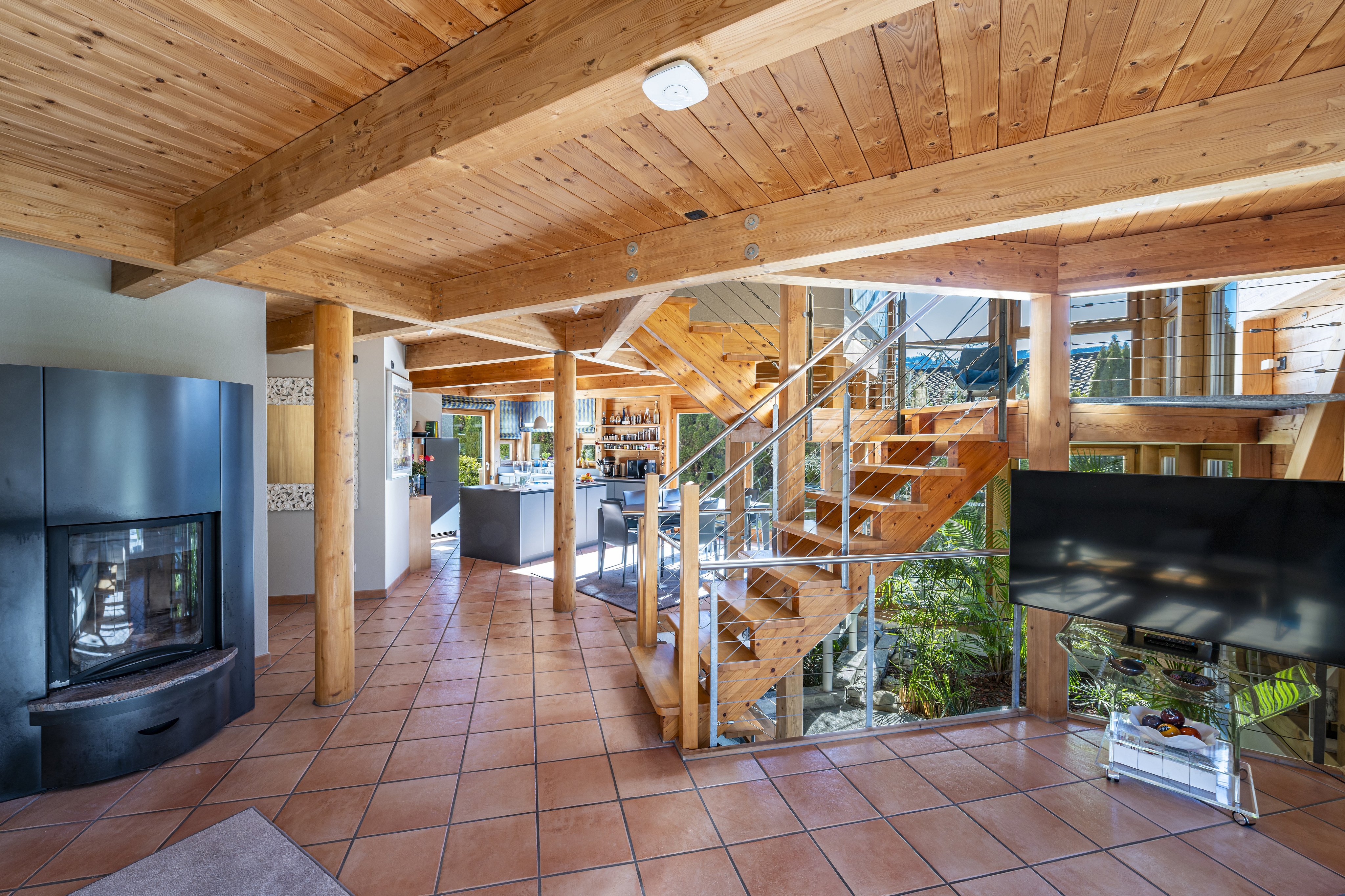 Offener Wohnbereich mit Holztreppe und Kamin