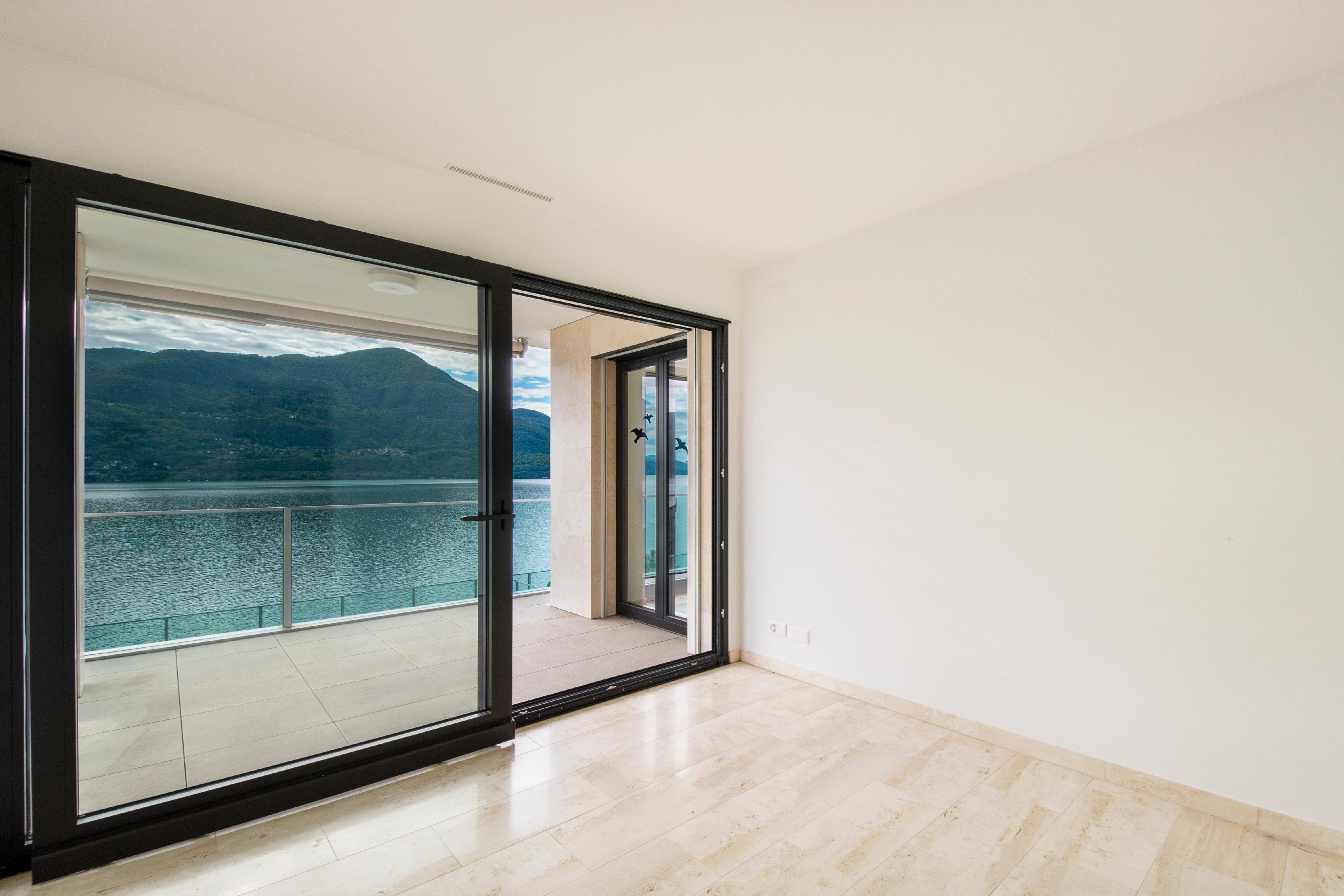 Leerer Wohnraum mit großer Glasfront und Seeblick