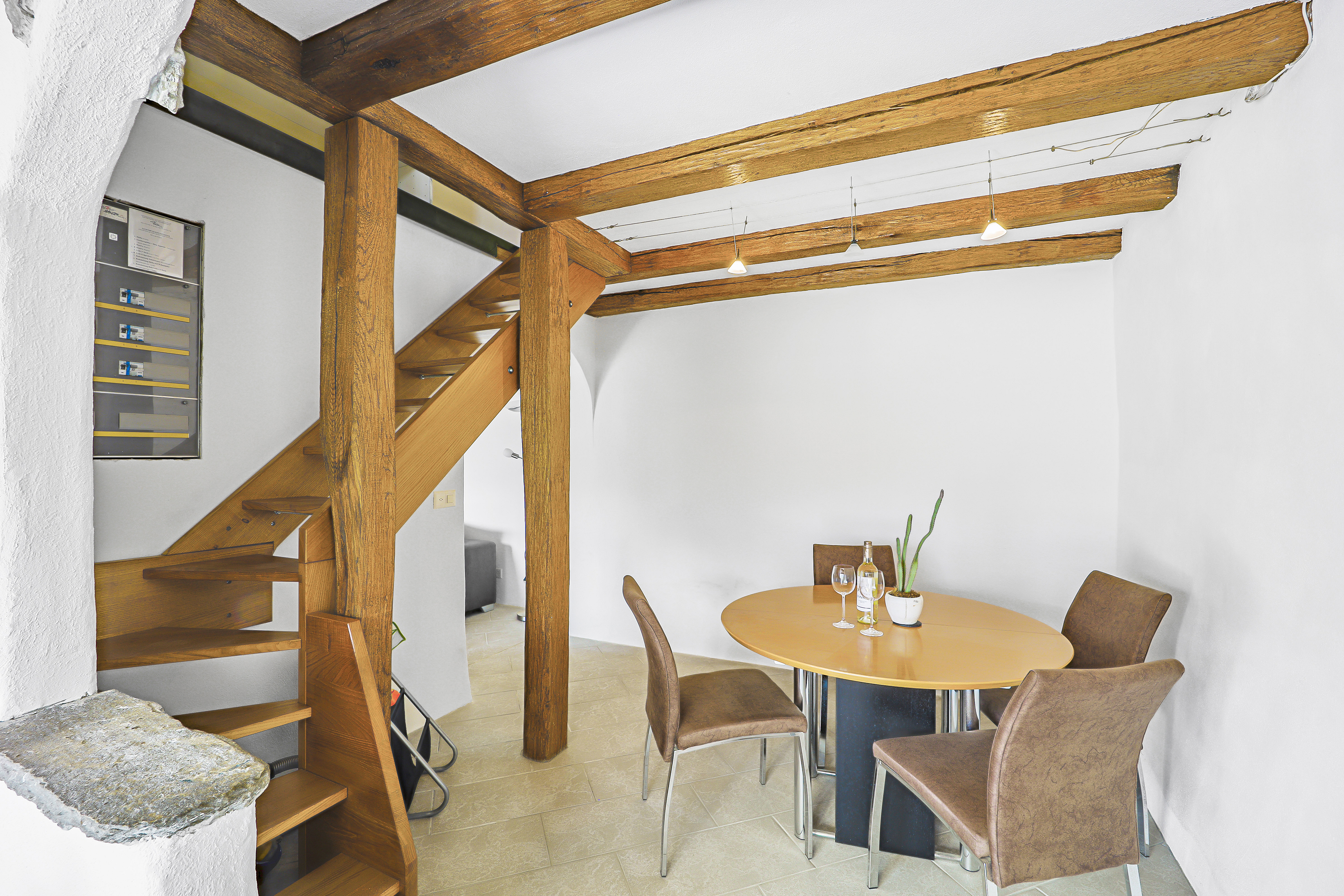 Gemütlicher Essbereich mit Holztreppe und sichtbaren Deckenbalken