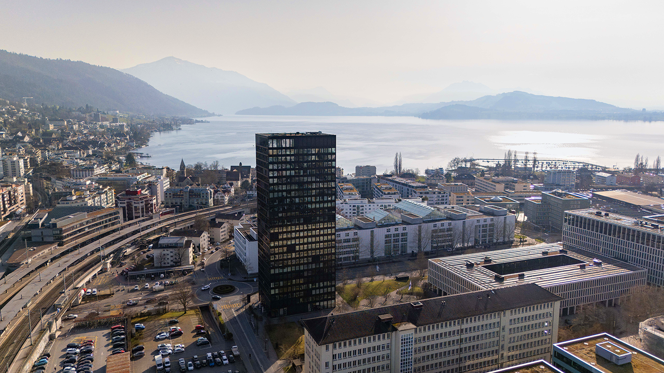 Städtischer Seeblick mit Hochhaus und Bergen