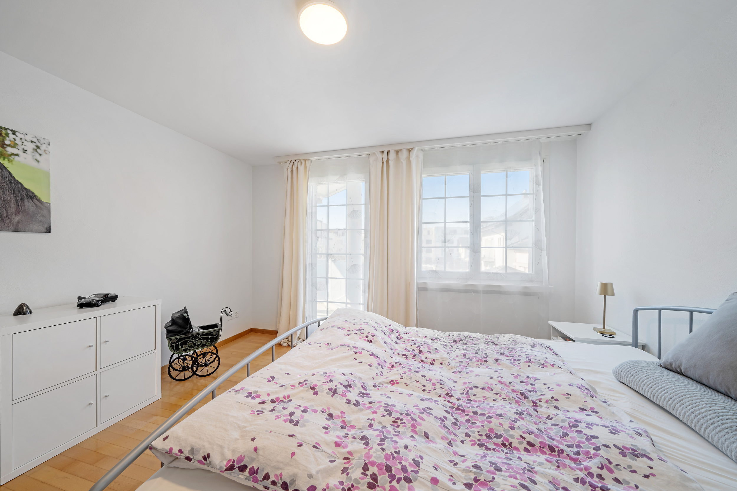 Helles Schlafzimmer mit Doppelbett und Fensterfront