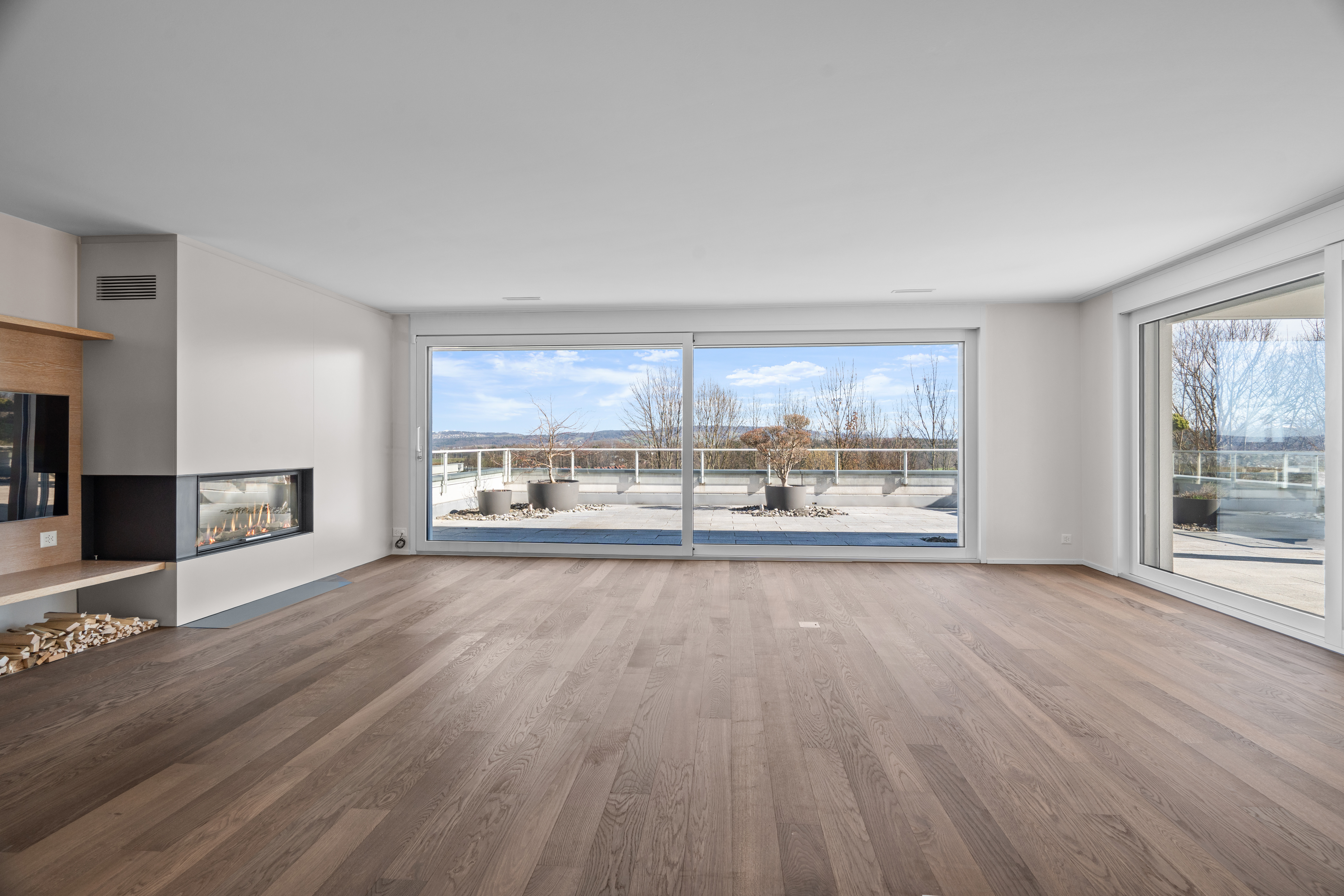 Offener Wohnraum mit Panoramafenstern und Kamin