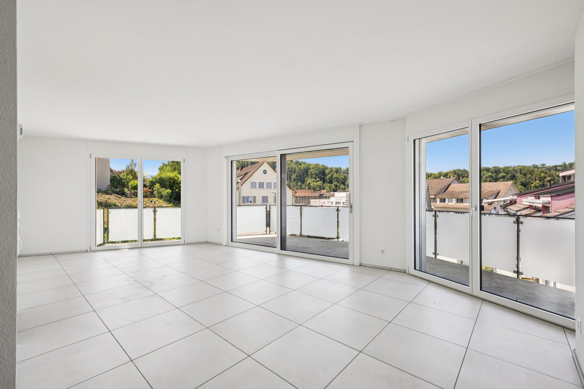 Heller leerer Wohnraum mit Balkon und großer Fensterfront