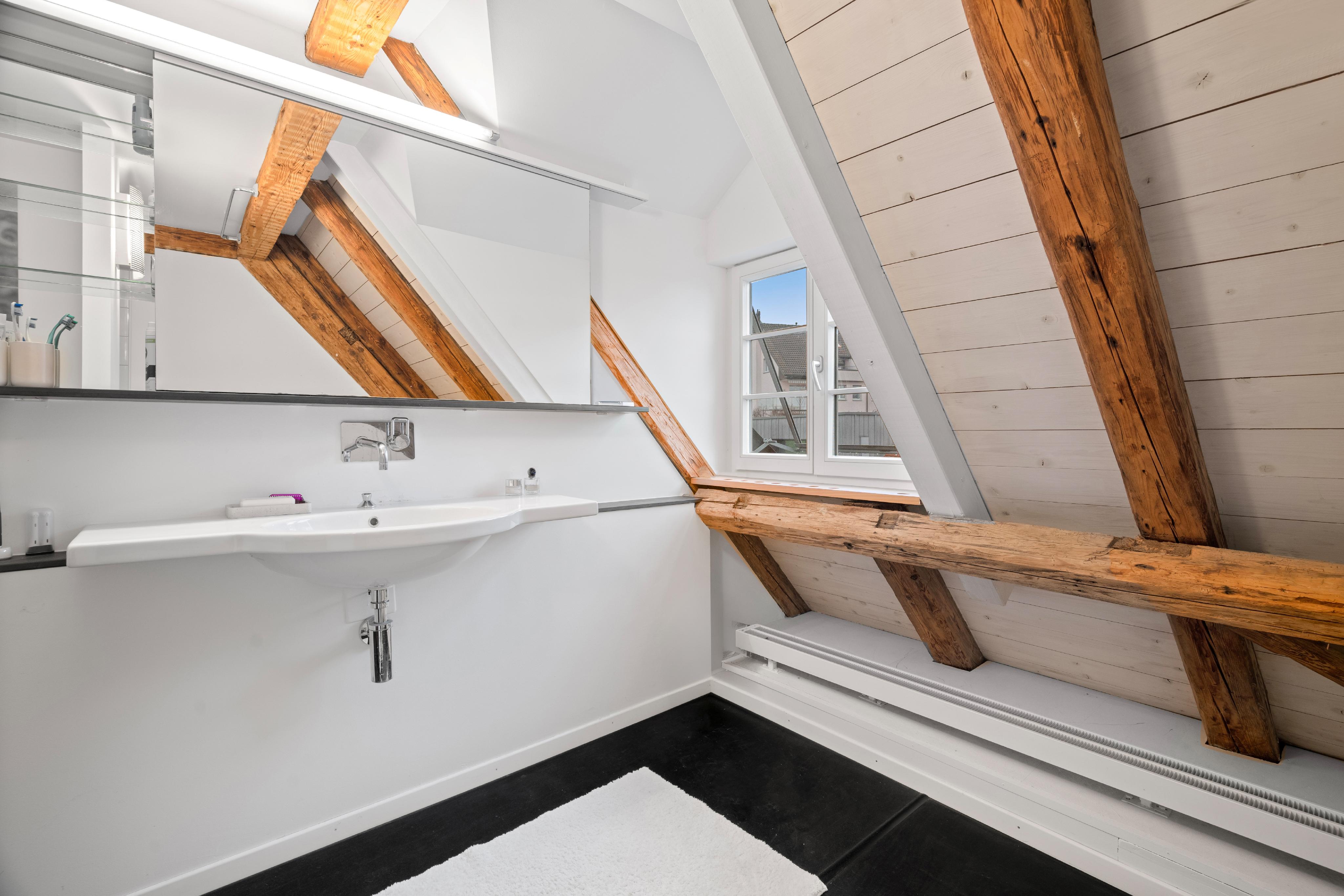 Helles Dachgeschoss-Badezimmer mit sichtbaren Holzbalken