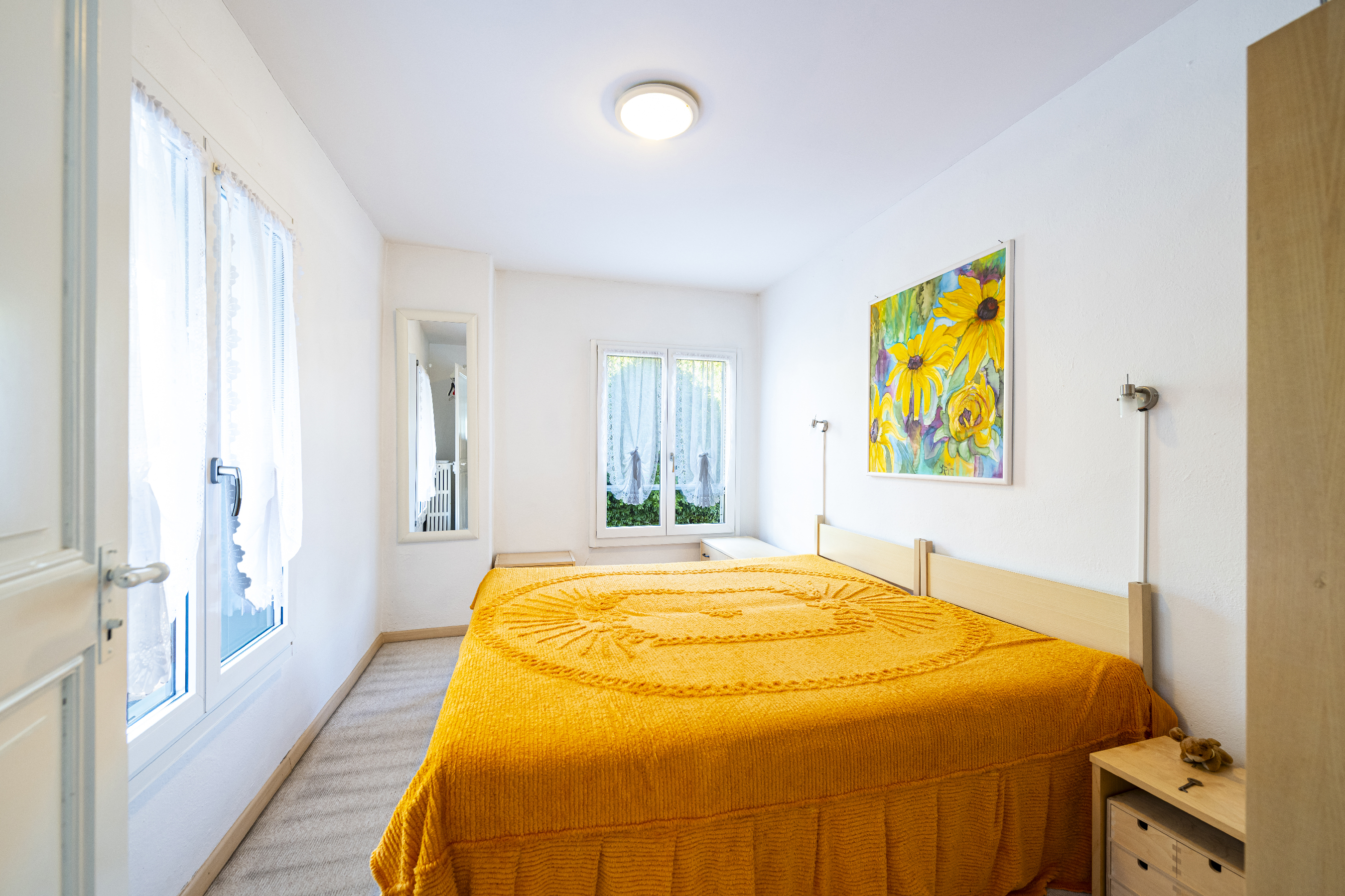 Helles Schlafzimmer mit gelbem Bettüberwurf